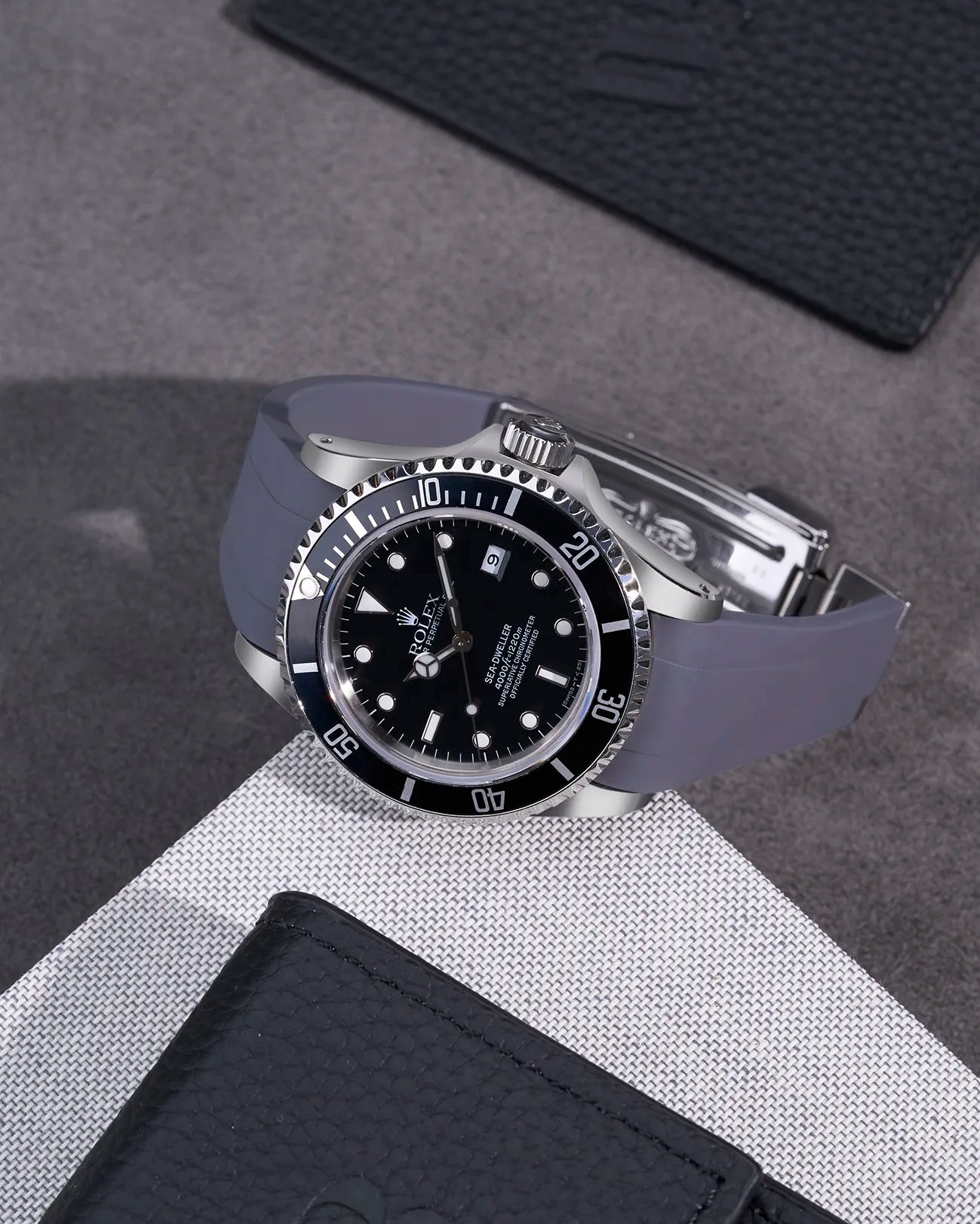 Rolex Sea-Dweller 16600 fitted with grey FKM rubber strap and original clasp – styled on fabric background