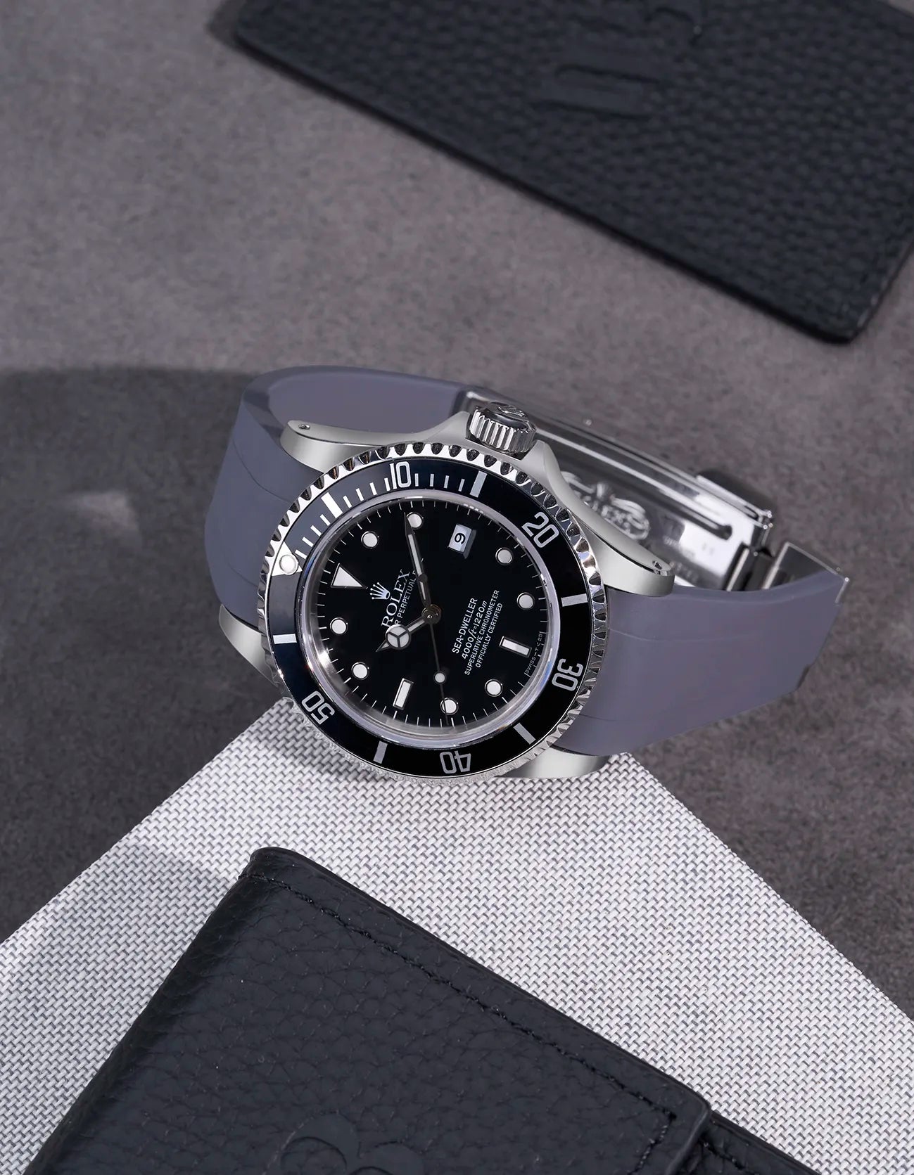 Rolex Sea-Dweller 16600 fitted with grey FKM rubber strap and original clasp – styled on fabric background