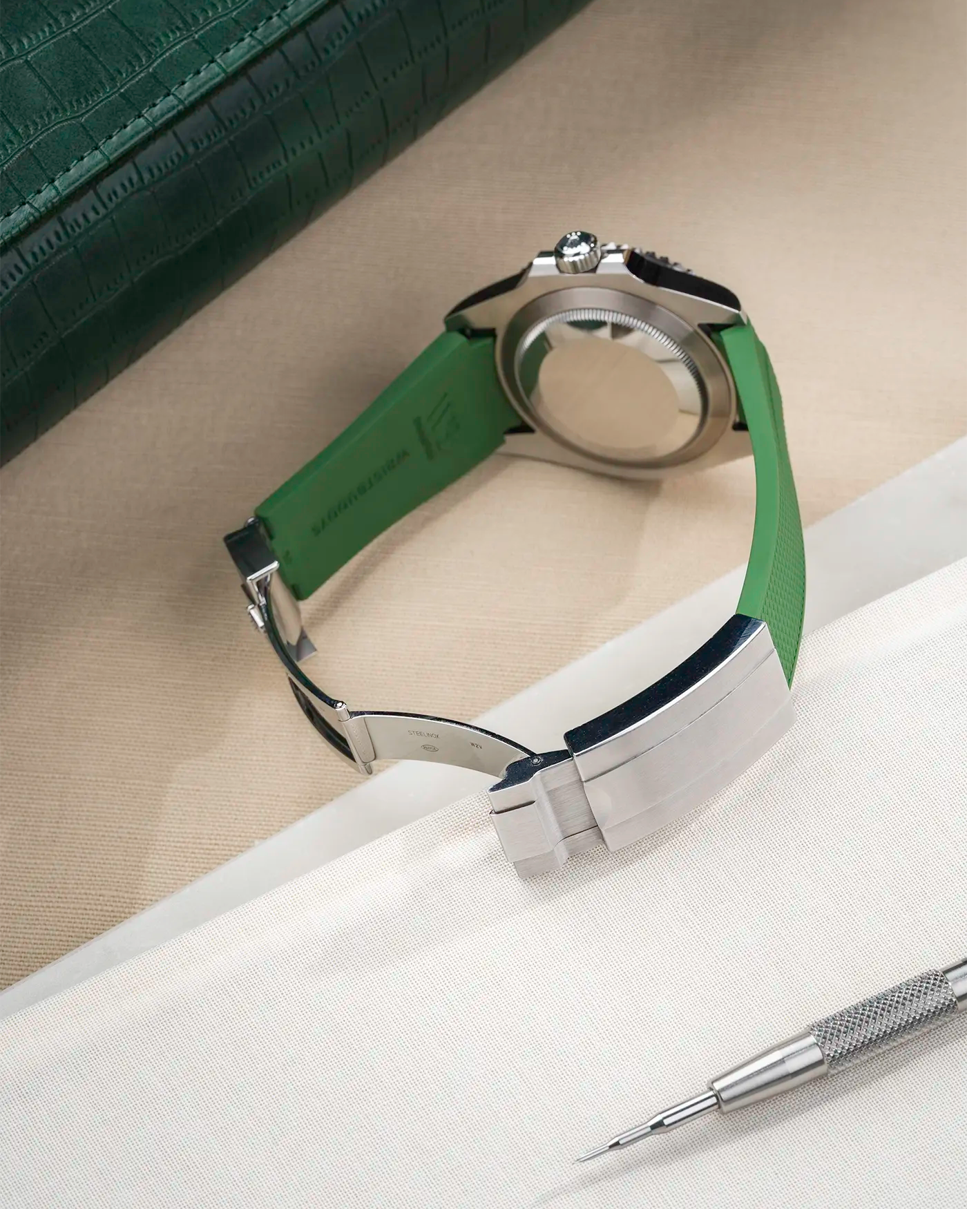 Back view product photo of Rolex Submariner 41 with green Classic Smooth FKM Rubber Strap sitting on the watch, integrated with original clasp – clasp open and watch case visible