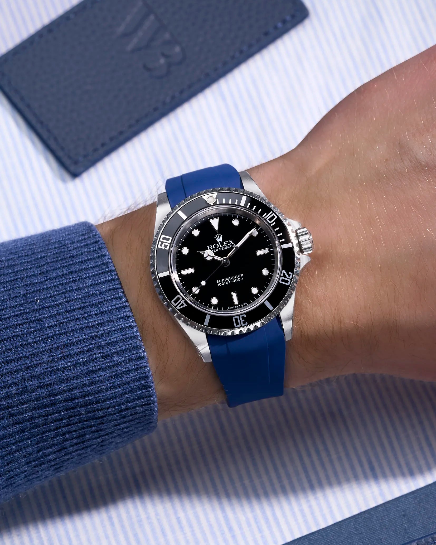 Blue rubber strap integrated with original Rolex clasp on Submariner 16610/14060 – wrist view on blue background
