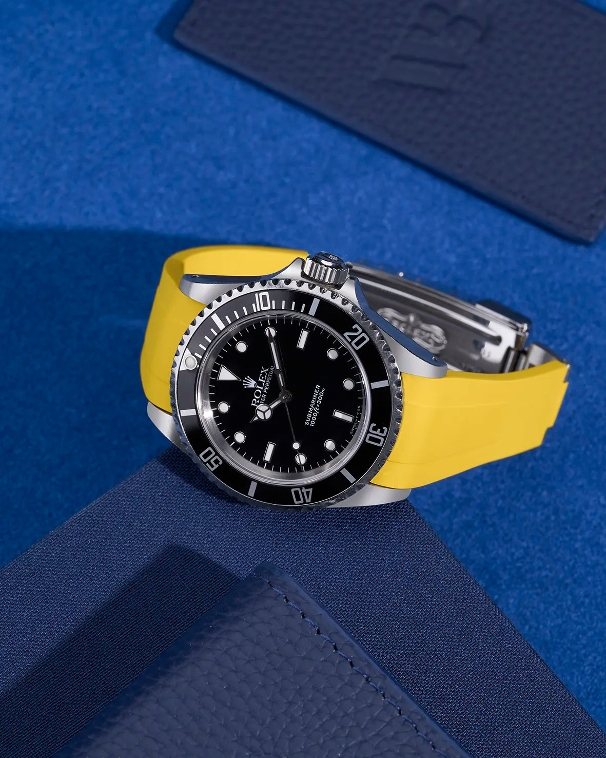 Rolex Submariner 16610 and 14060 with yellow FKM rubber strap and original clasp – styled on dark blue accessories