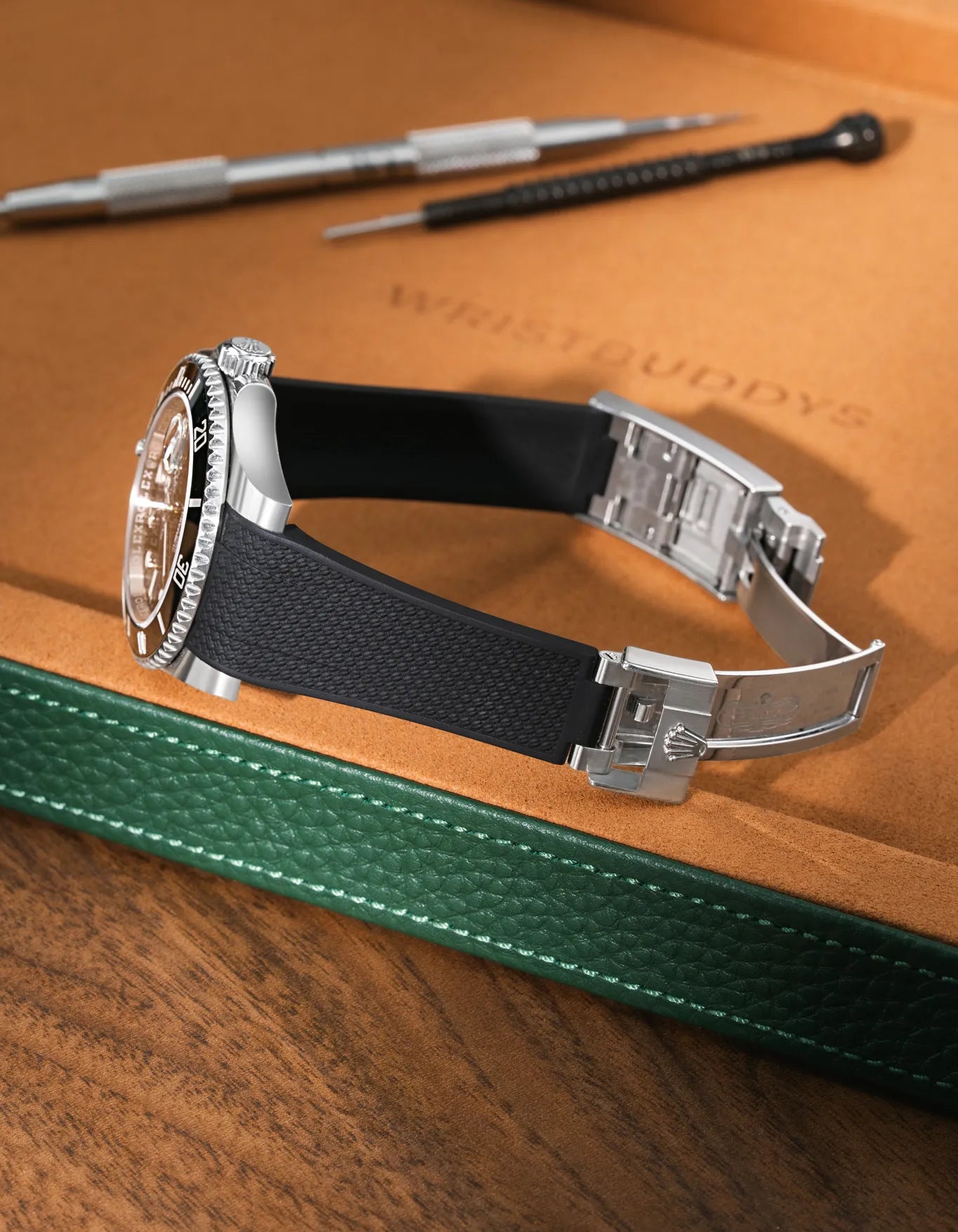 Black Vertech FKM rubber strap for Rolex Submariner 116610 and 126610, integrated fit for original clasp, resting on a leather valet tray.