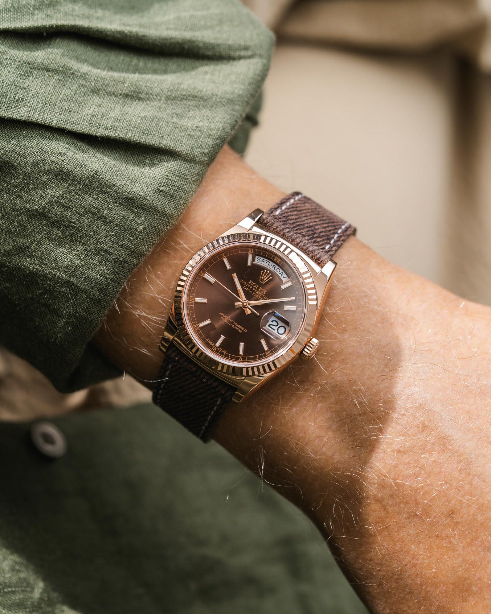 Close-up of a wrist wearing a brown leather denim watch strap on a Rolex DayDate in rosegold