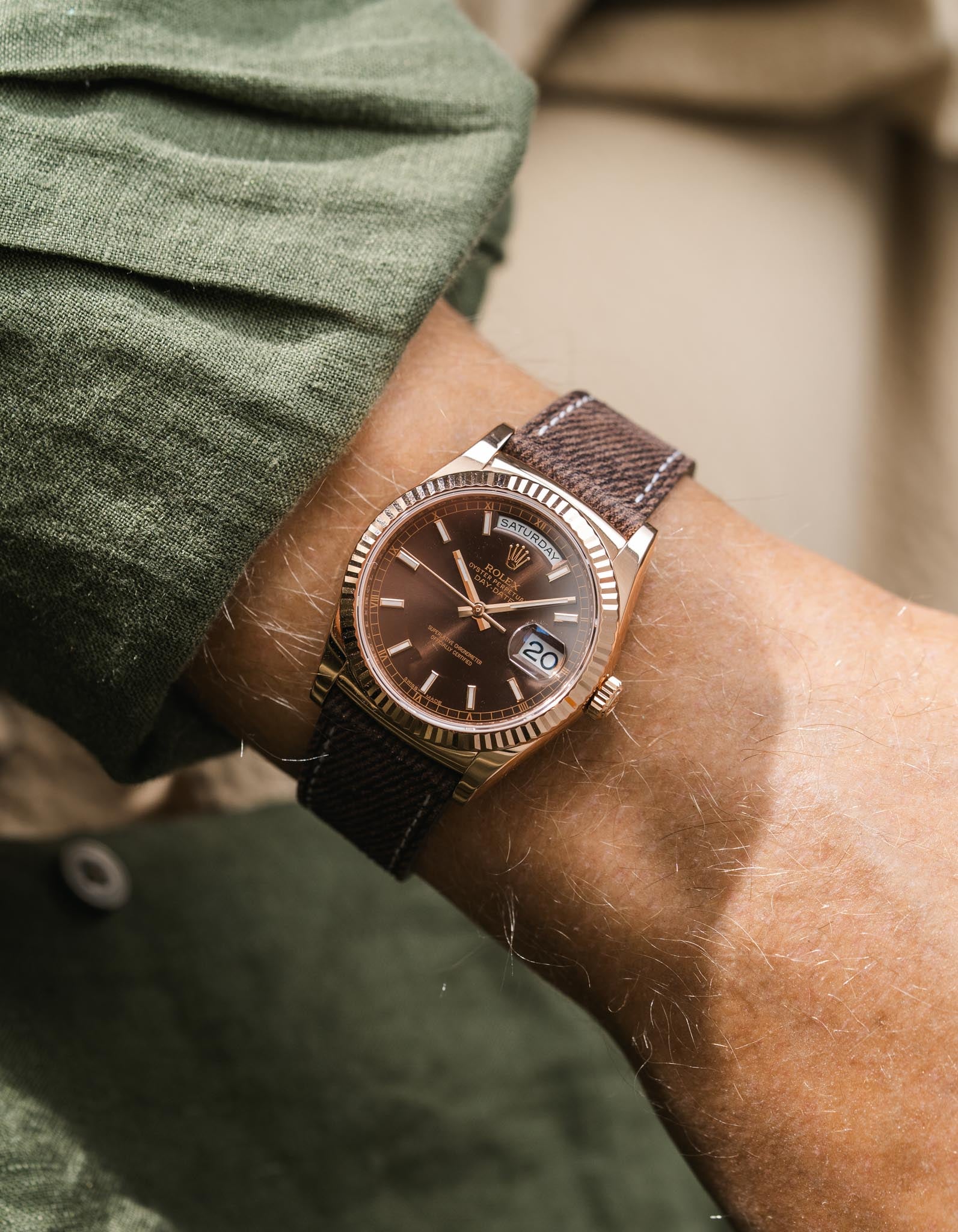Close-up of a wrist wearing a brown leather denim watch strap on a Rolex DayDate in rosegold