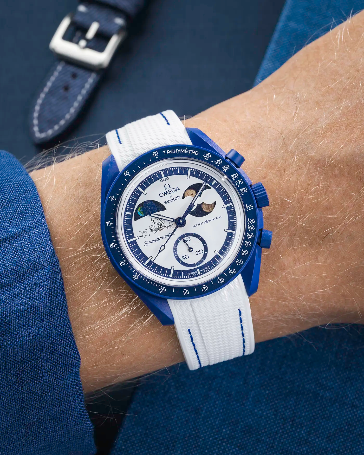 MoonSwatch Mission to Earthphase – Moonshine Gold with white rubber strap and blue stitching, wrist shot over blue background