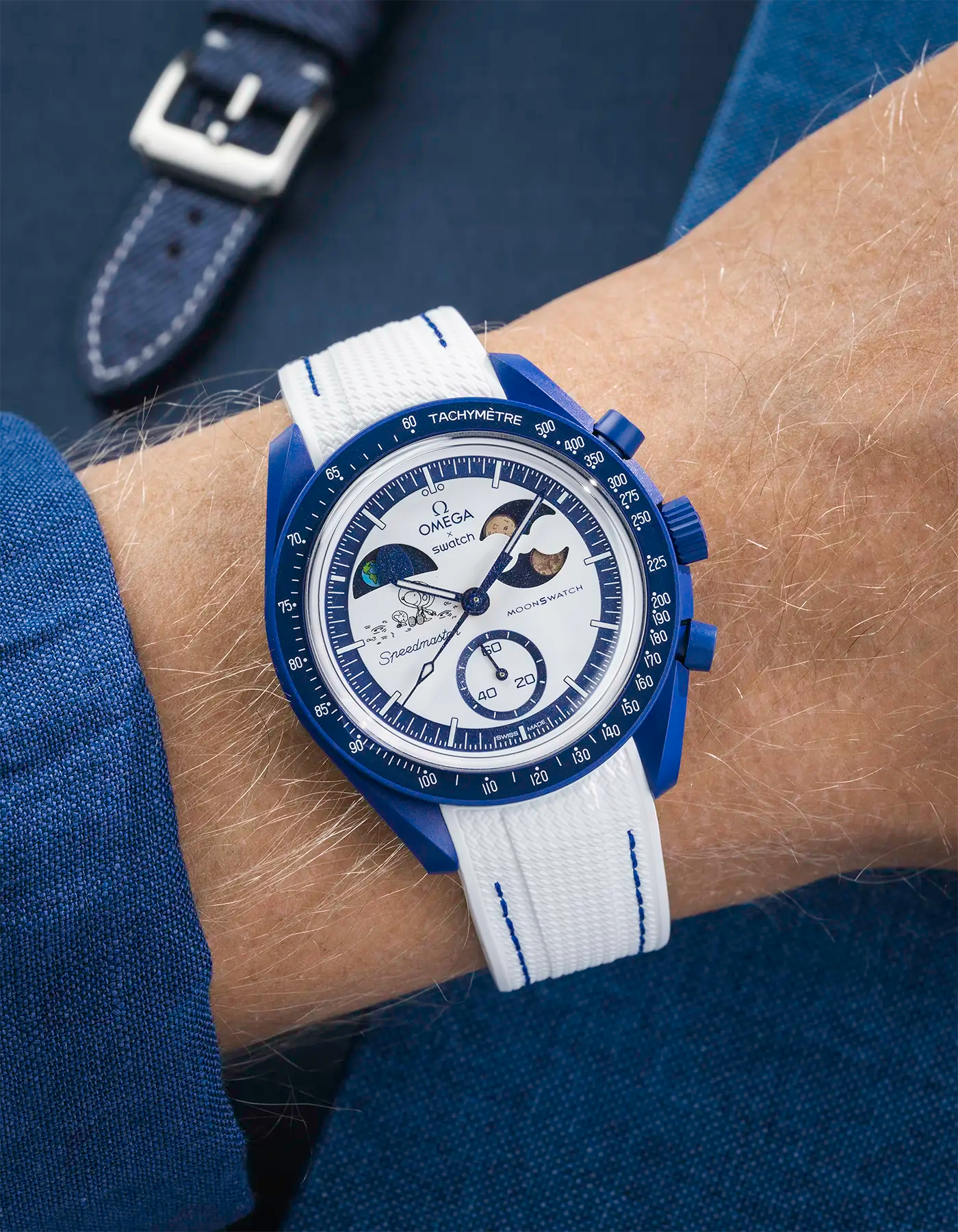 MoonSwatch Mission to Earthphase – Moonshine Gold with white rubber strap and blue stitching, wrist shot over blue background