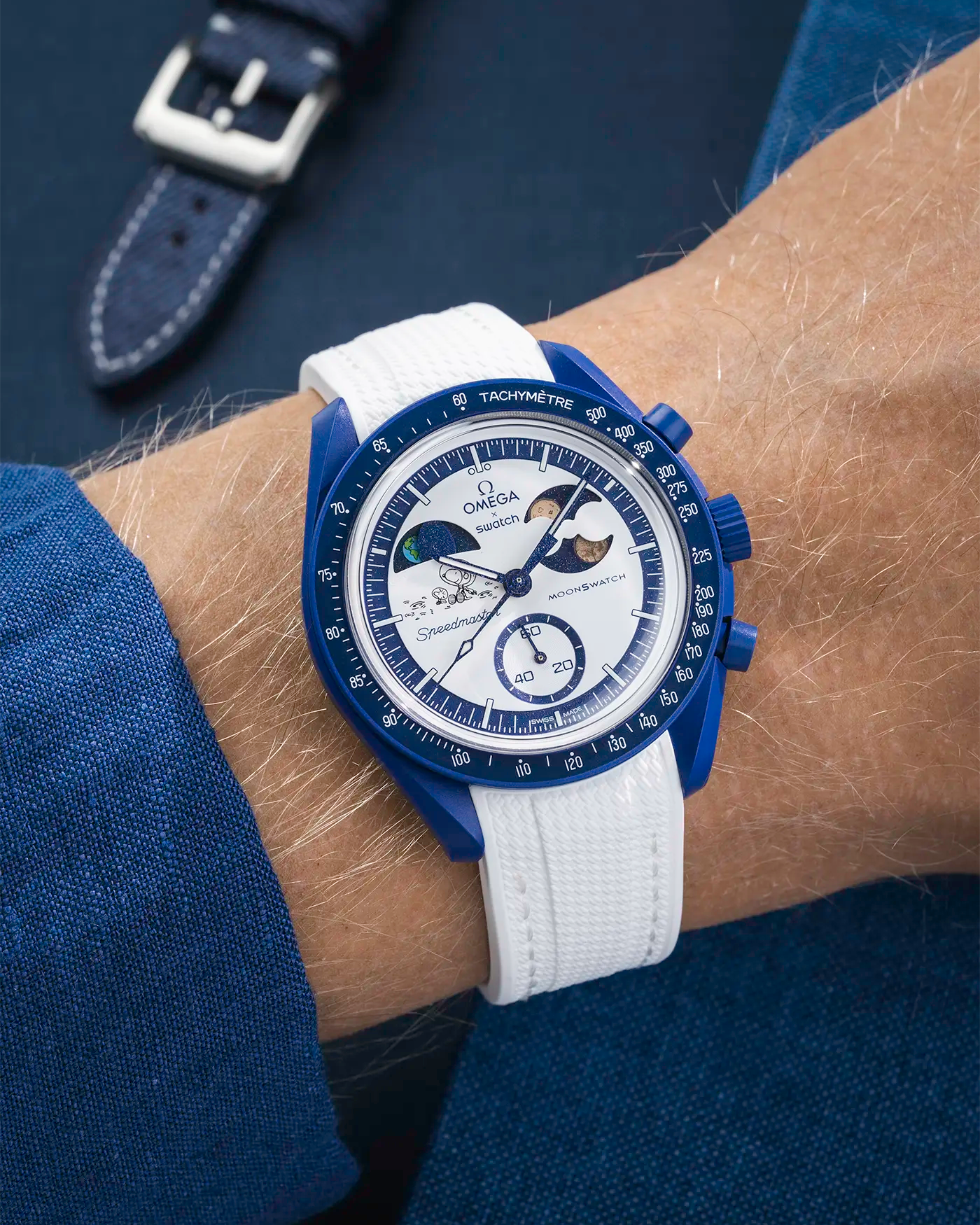 MoonSwatch Mission to Earthphase – Moonshine Gold with white rubber strap, wrist shot over blue background