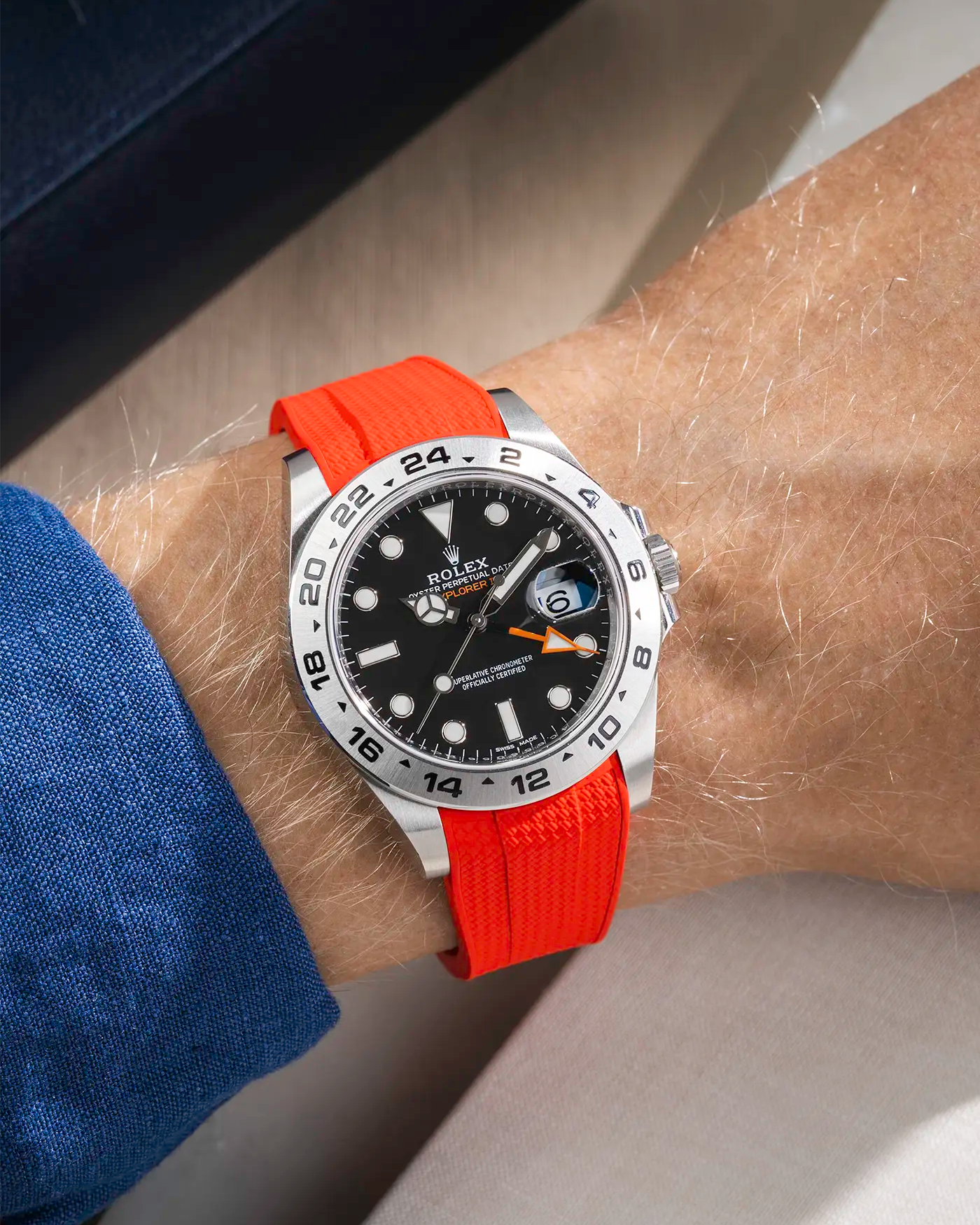 Wrist shot on Red Vertech FKM Rubber Strap Integrated with Original Clasp - Rolex Explorer 216570 over a table with a watch roll