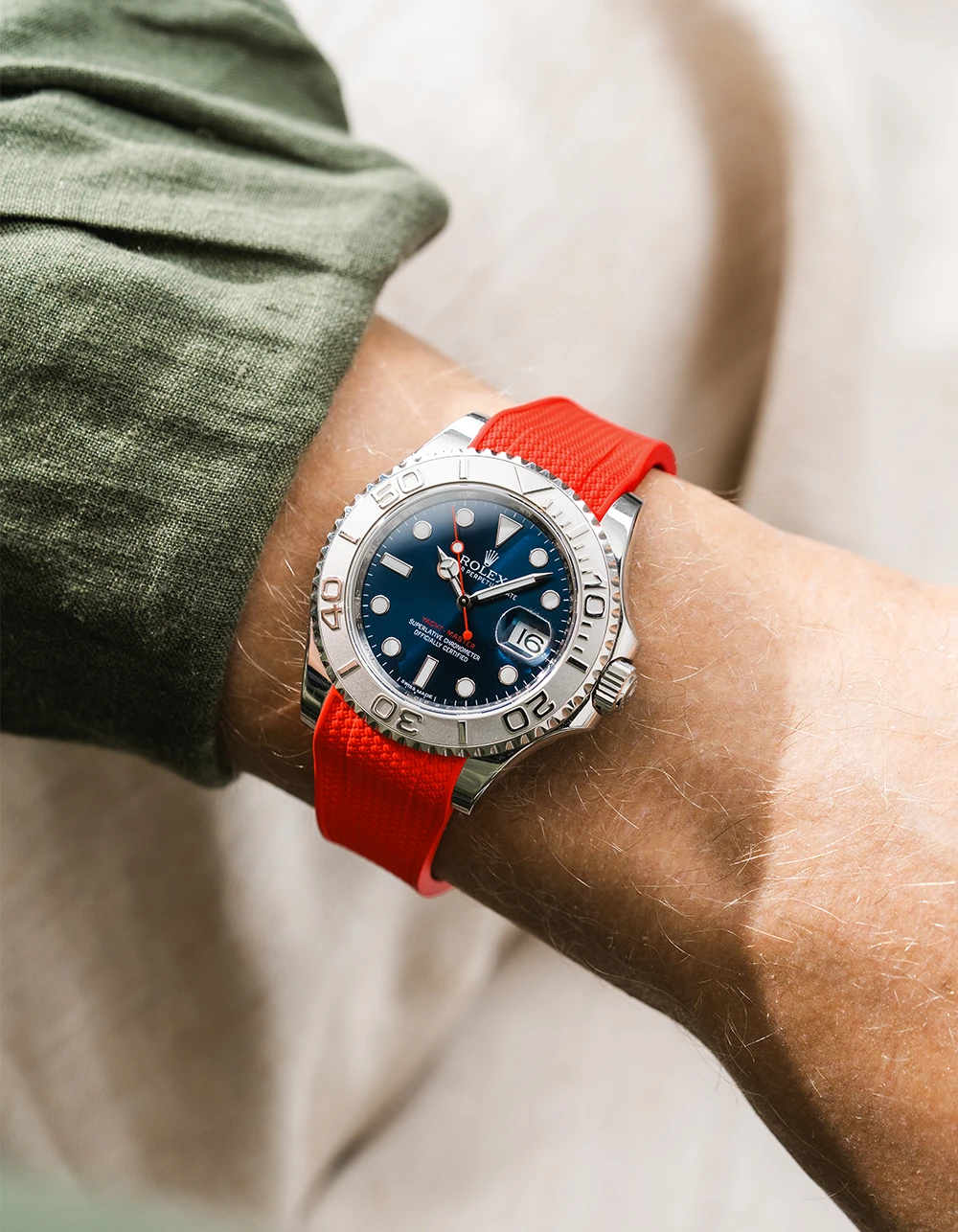 Close-up of a person wearing a Rolex YachtMaster 2 126622 / 116622 model watch with a dark green shirt sleeve and a red vertech FKM rubber watch strap from Wristbuddys