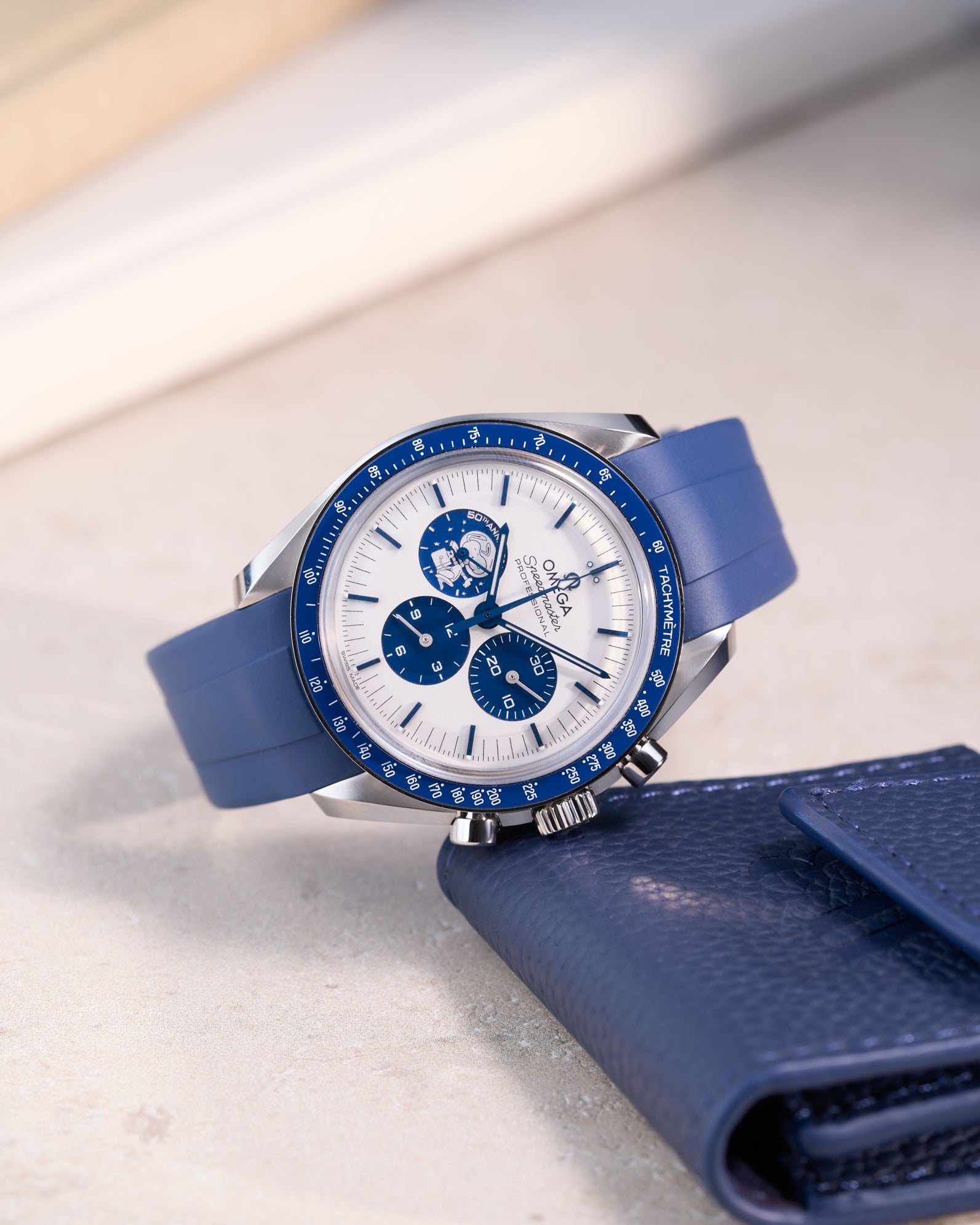 Omega Speedmaster Silver Snoopy Award watch with navy blue rubber band – angled detail shot with eatch pouch by Wristbuddys
