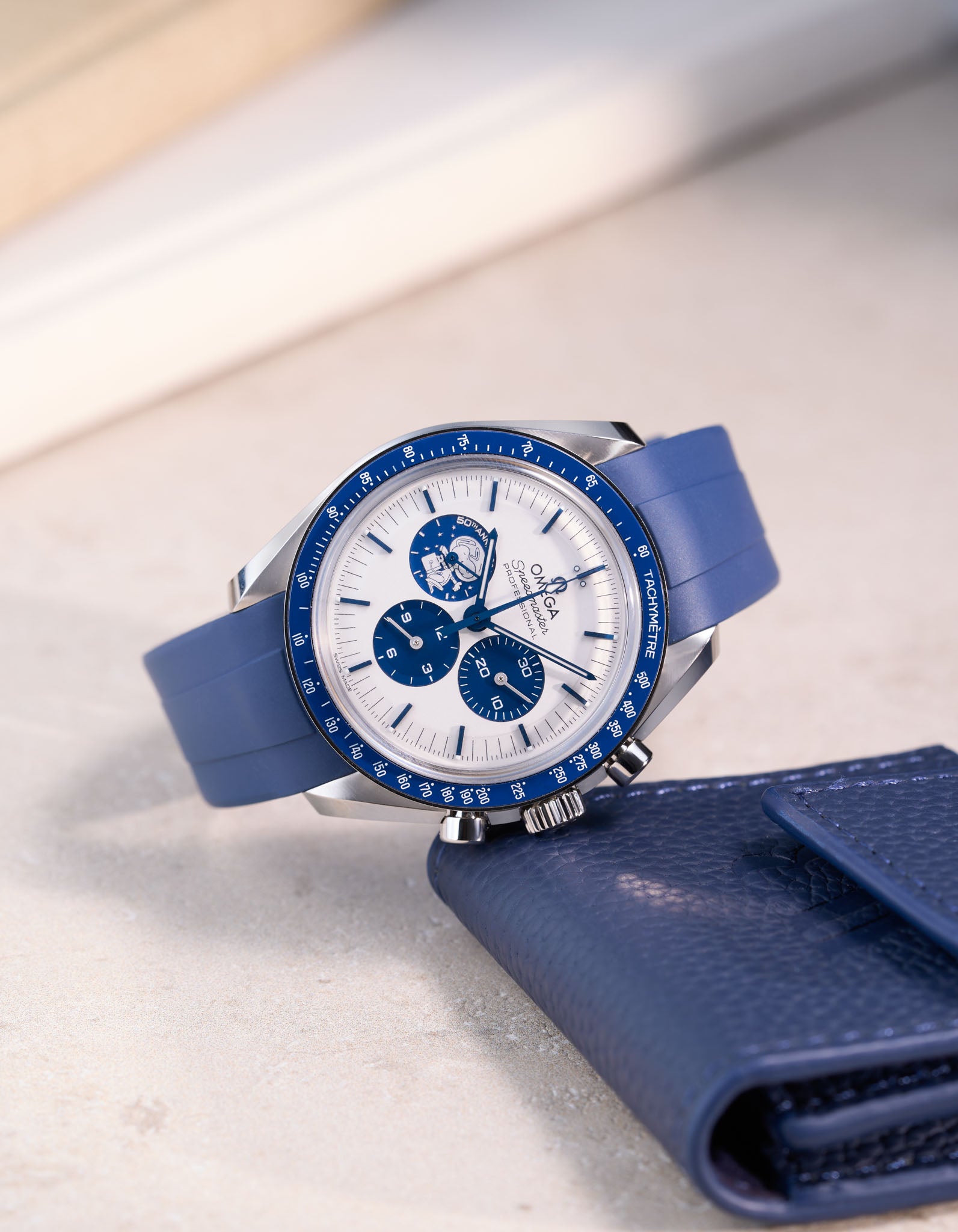 Omega Speedmaster Silver Snoopy Award watch with navy blue rubber band – angled detail shot with eatch pouch by Wristbuddys