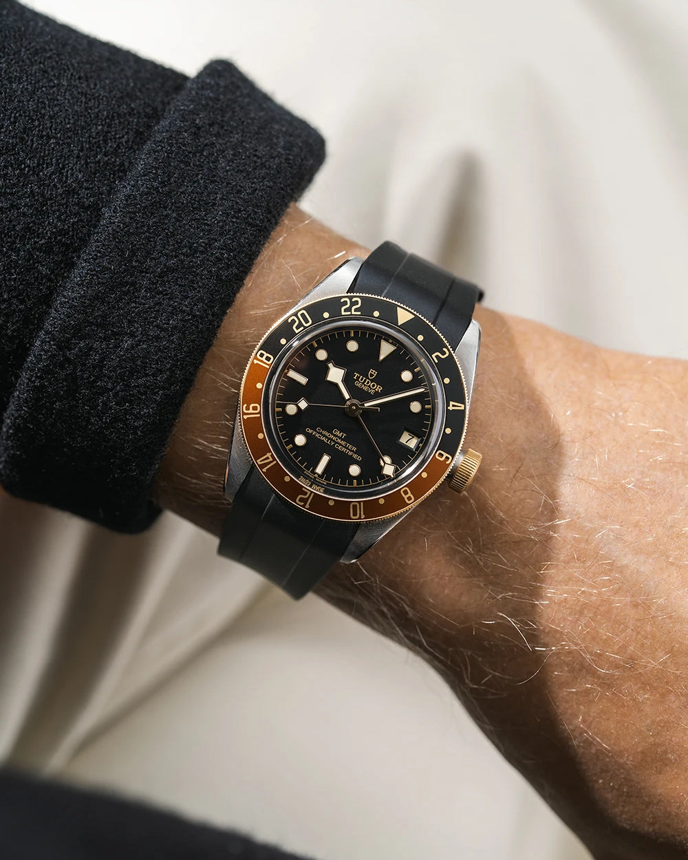 Tudor GMT two tone watch on a person's wrist with a black FKM rubber watch strap from Wristbuddys and red accents on the bezel