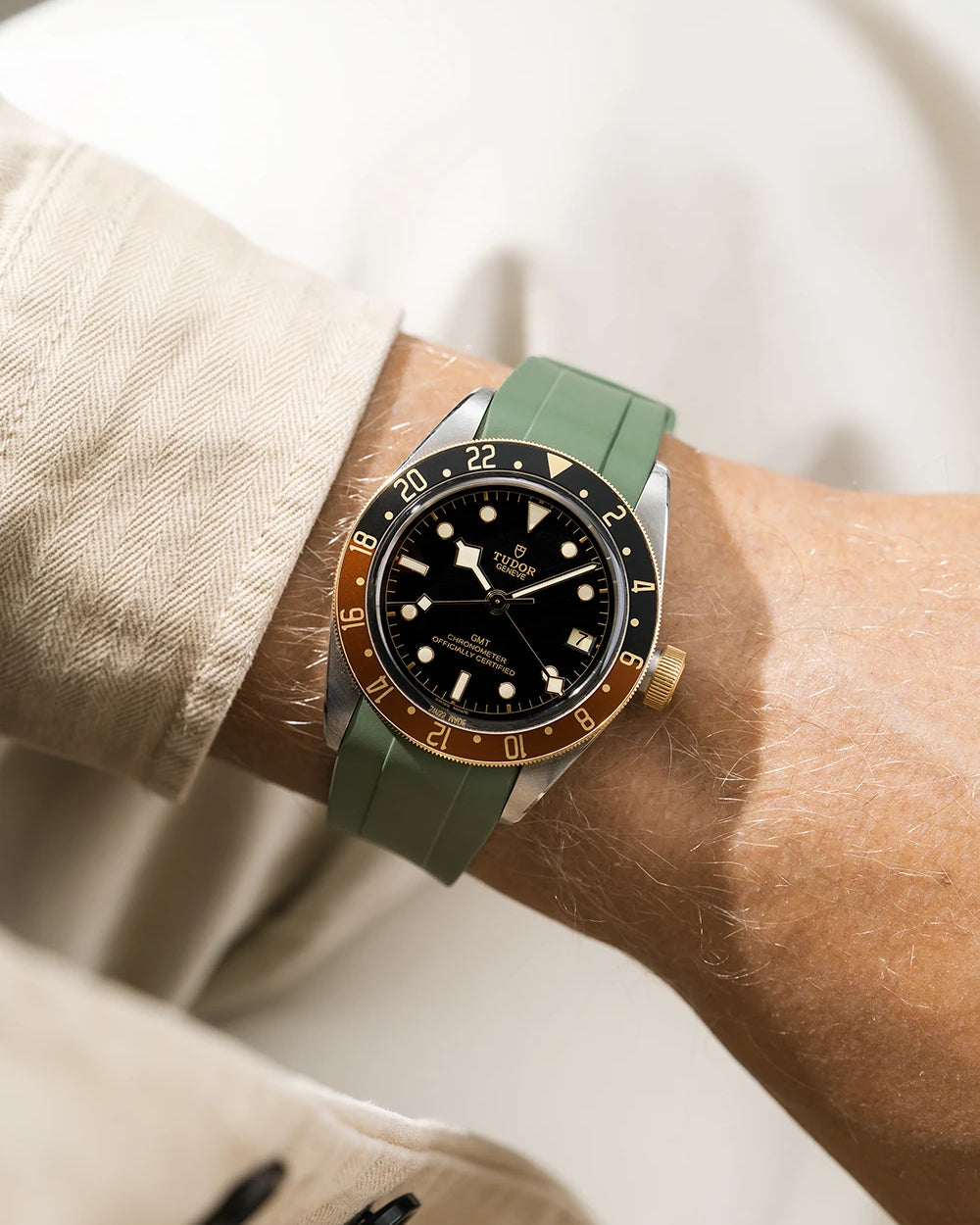 Tudor GMT two tone watch on a person's wrist with a green FKM rubber watch strap from Wristbuddys and brown accents on the bezel