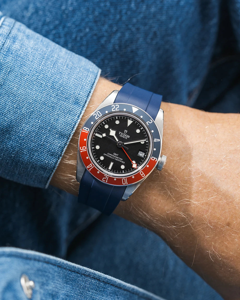 Tudor GMT watch on a person's wrist with a navy blue FKM rubber watch strap from Wristbuddys and red accents on the bezel