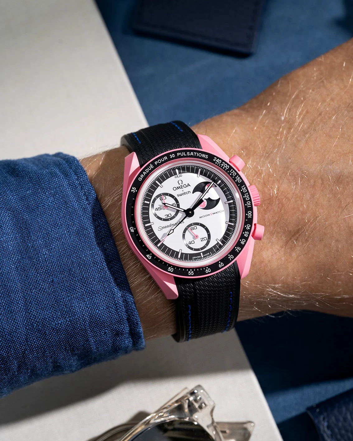 Black curved vertech rubber strap with blue stitches on MoonSwatch Mission to The Pink Moonphase wrist shot