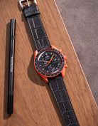 Flat lay of black embossed alligator leather strap for Omega x Swatch MoonSwatch mission on Earth Lava