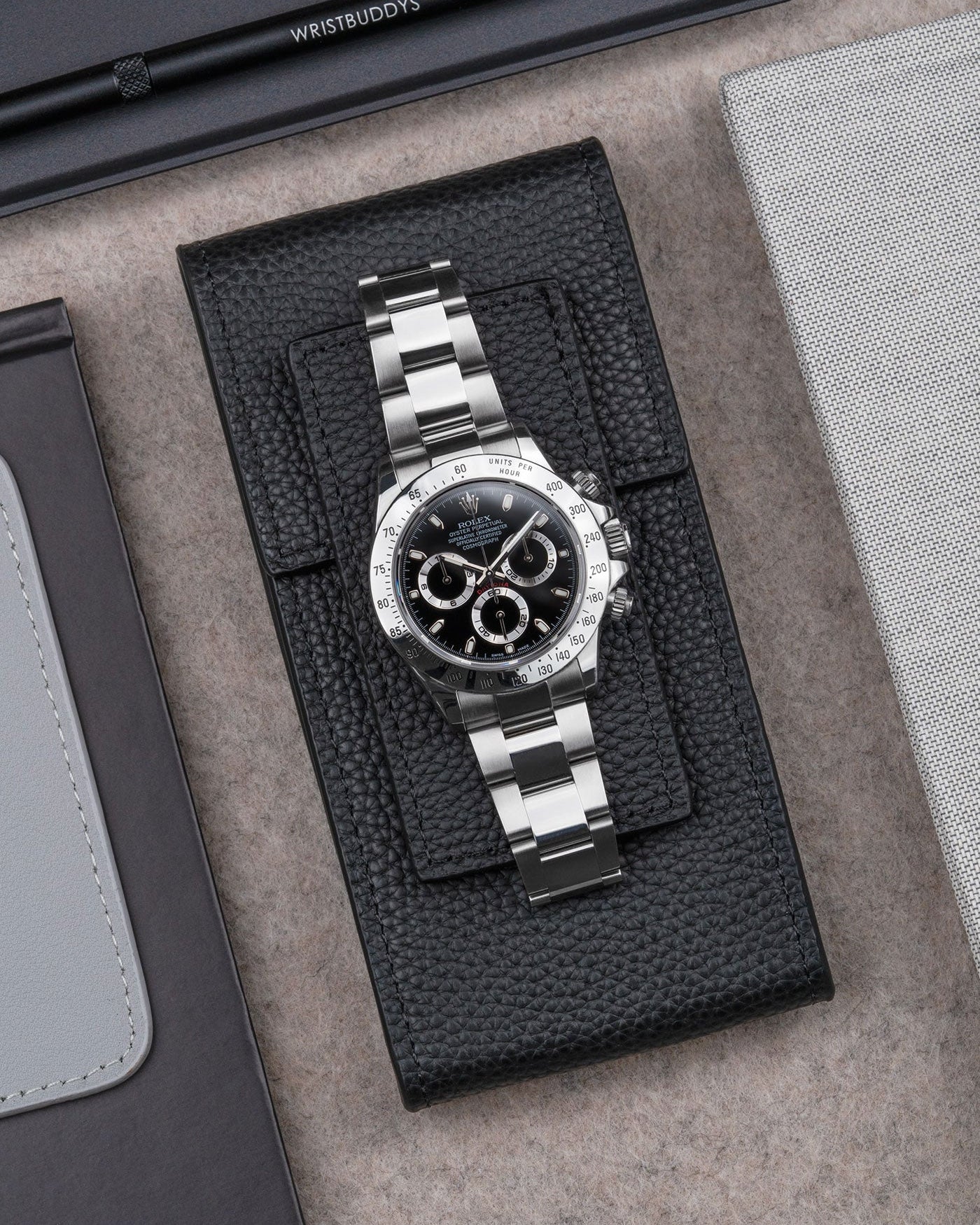Rolex Daytona displayed on Black leather watch pouch by Wristbuddys – elegant flat lay product photo of luxury watch case
