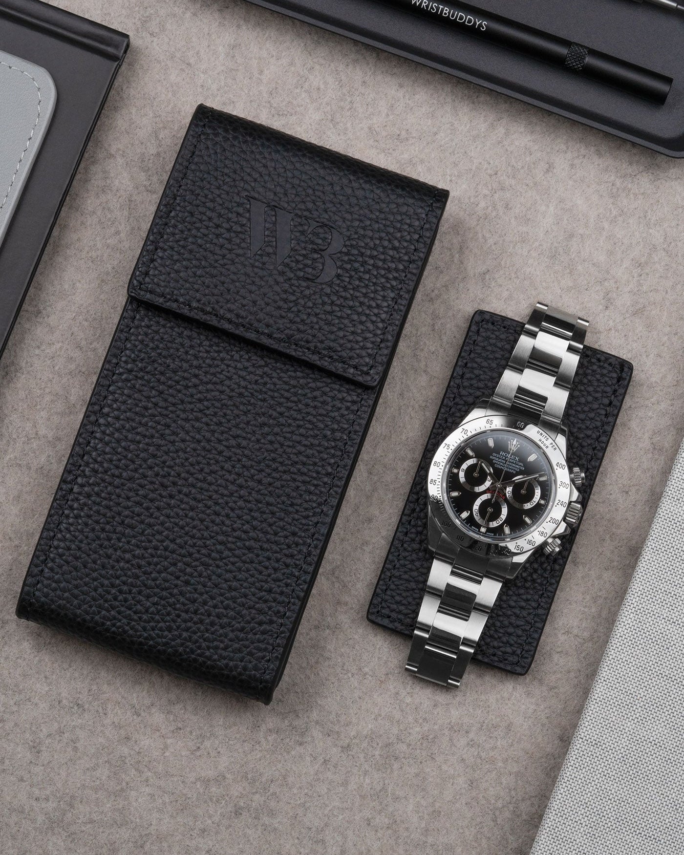 Black leather watch pouch by Wristbuddys with Rolex Daytona resting on pouch lid – luxury travel case for watches