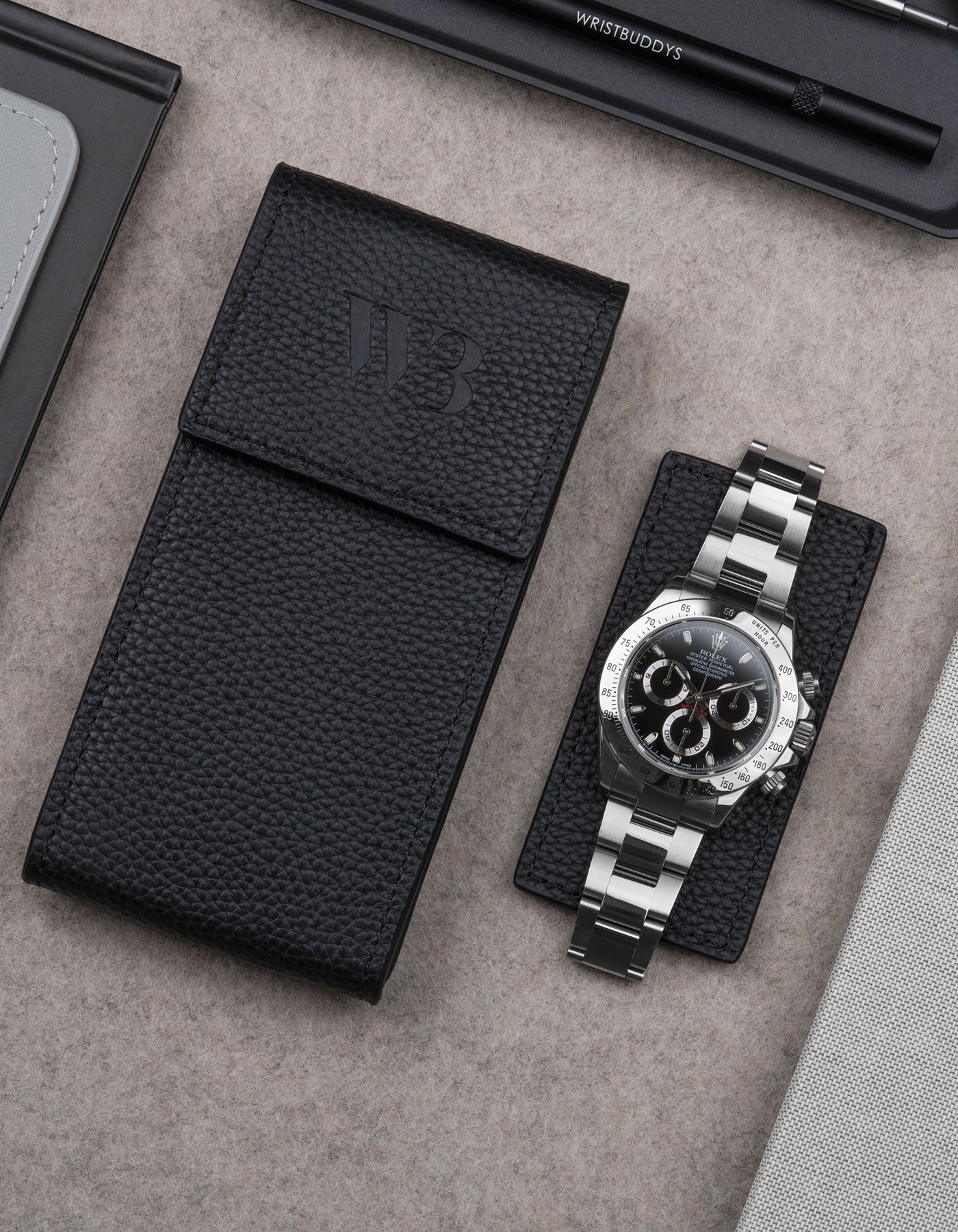 Black leather watch pouch by Wristbuddys with Rolex Daytona resting on pouch lid – luxury travel case for watches