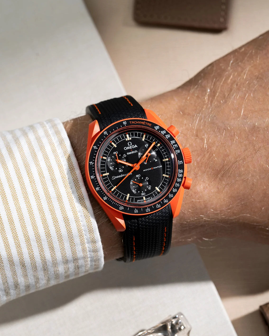 Wrist shot showing black rubber strap with orange stitching for Omega X Swatch MoonSwatch Mission On Earth Lava