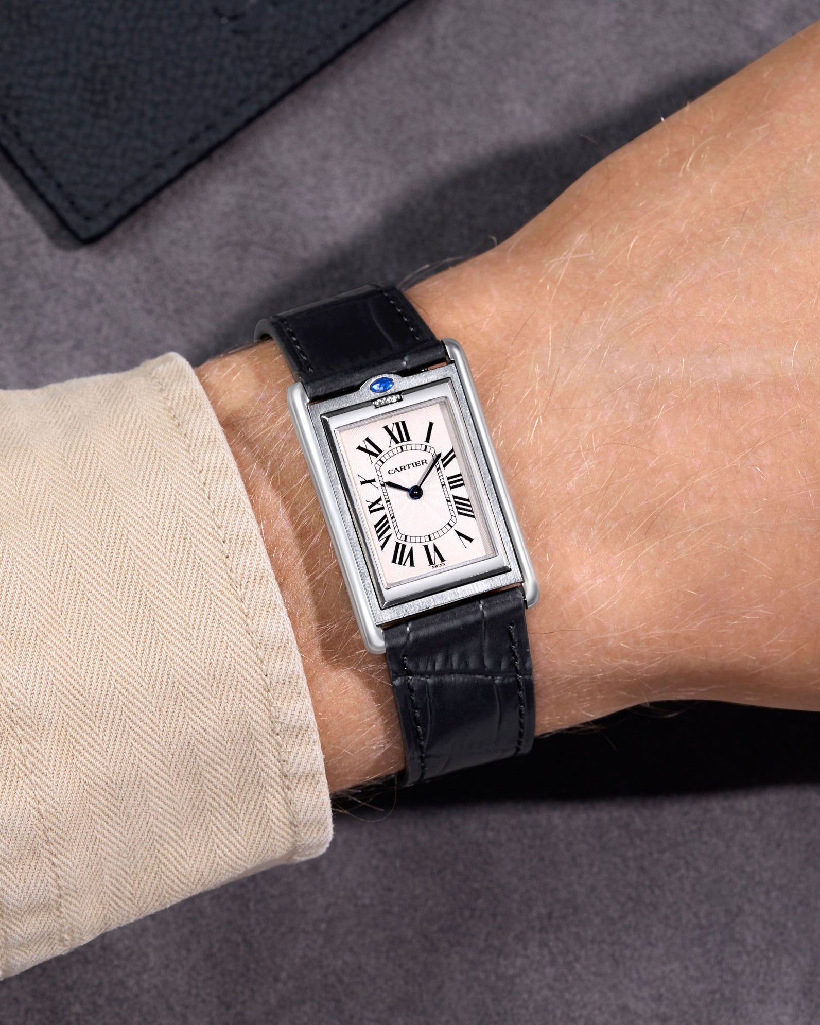 Cartier steel watch with a black embossed alligator leather watch strap on a black background