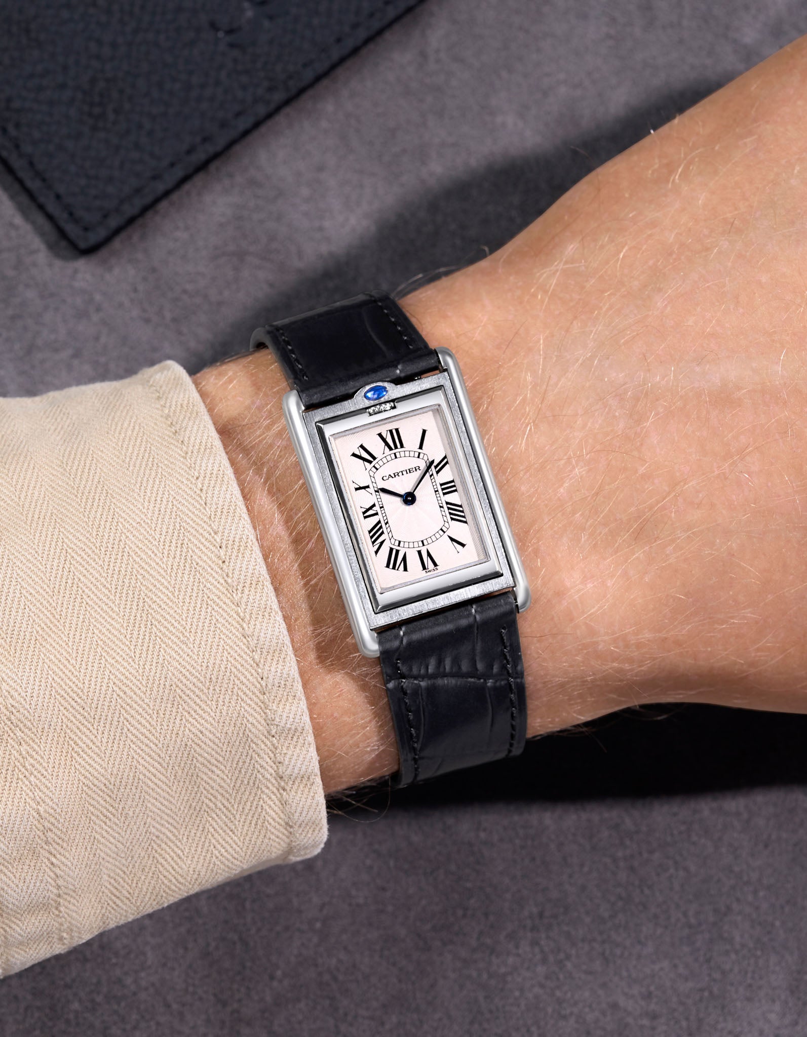 Cartier steel watch with a black embossed alligator leather watch strap on a black background