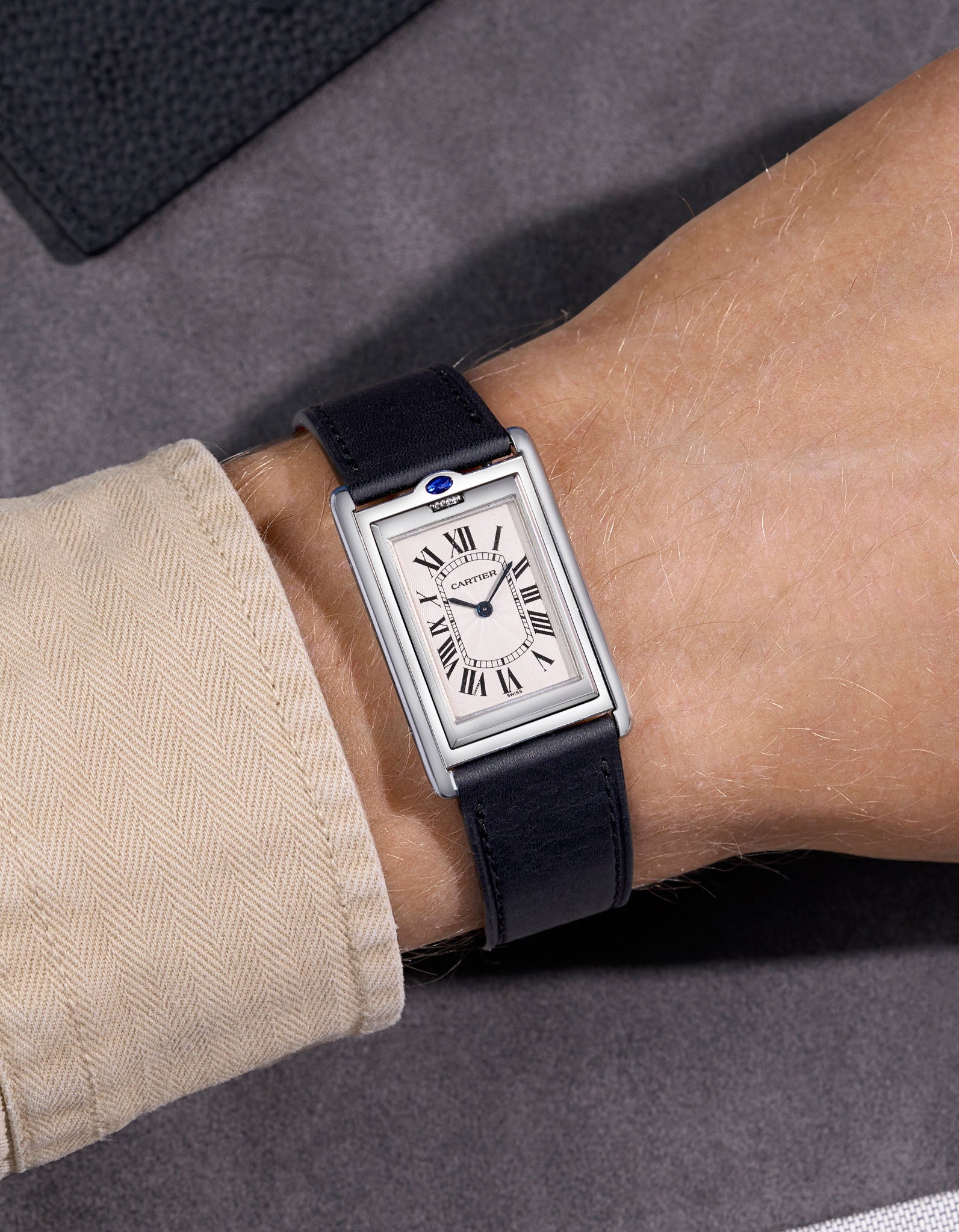 Cariter Basculante on a black cowhide leather watch strap on a wrist with a suede background