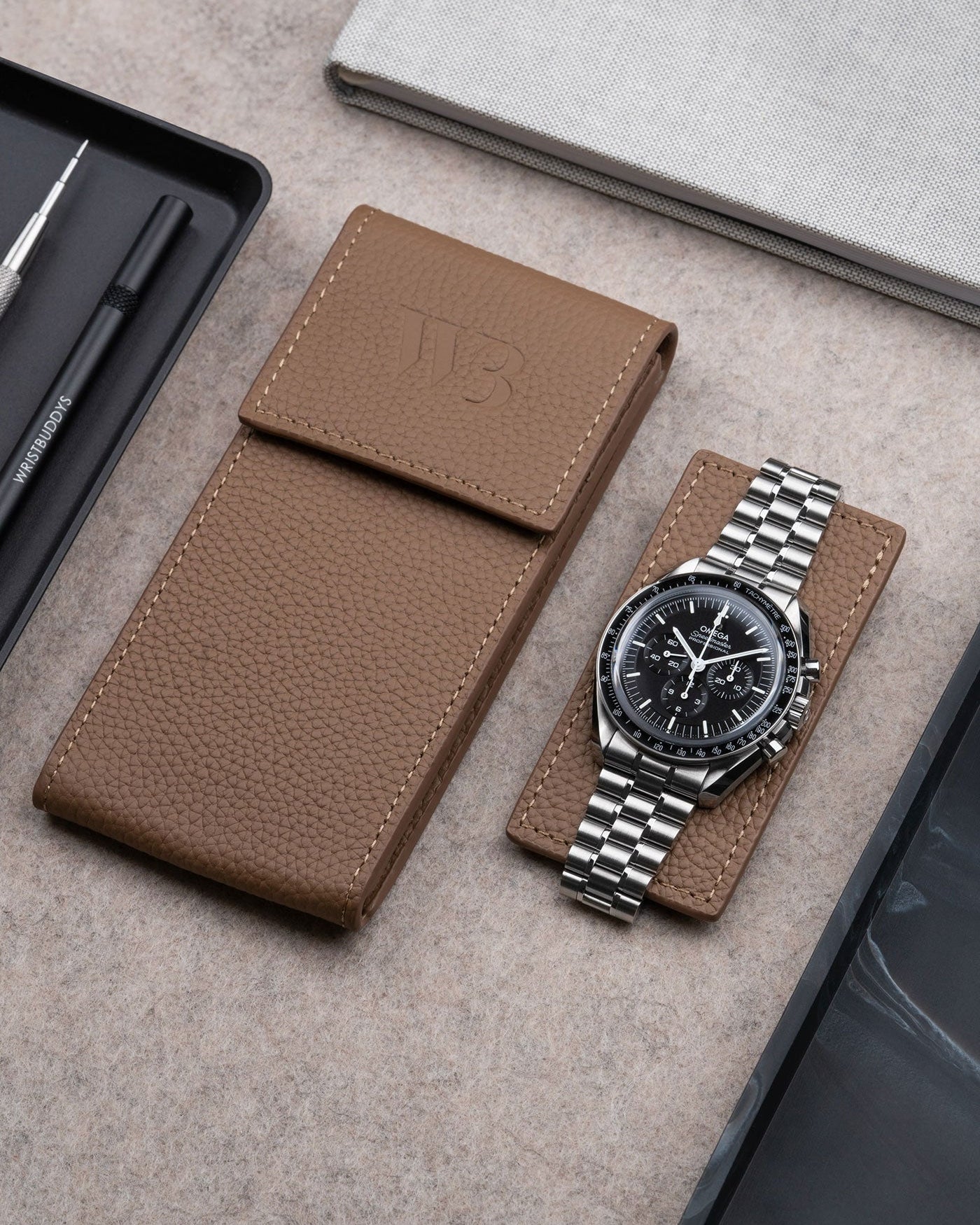 Brown leather watch pouch by Wristbuddys with Omega Speedmaster resting on pouch lid – luxury travel case for watches
