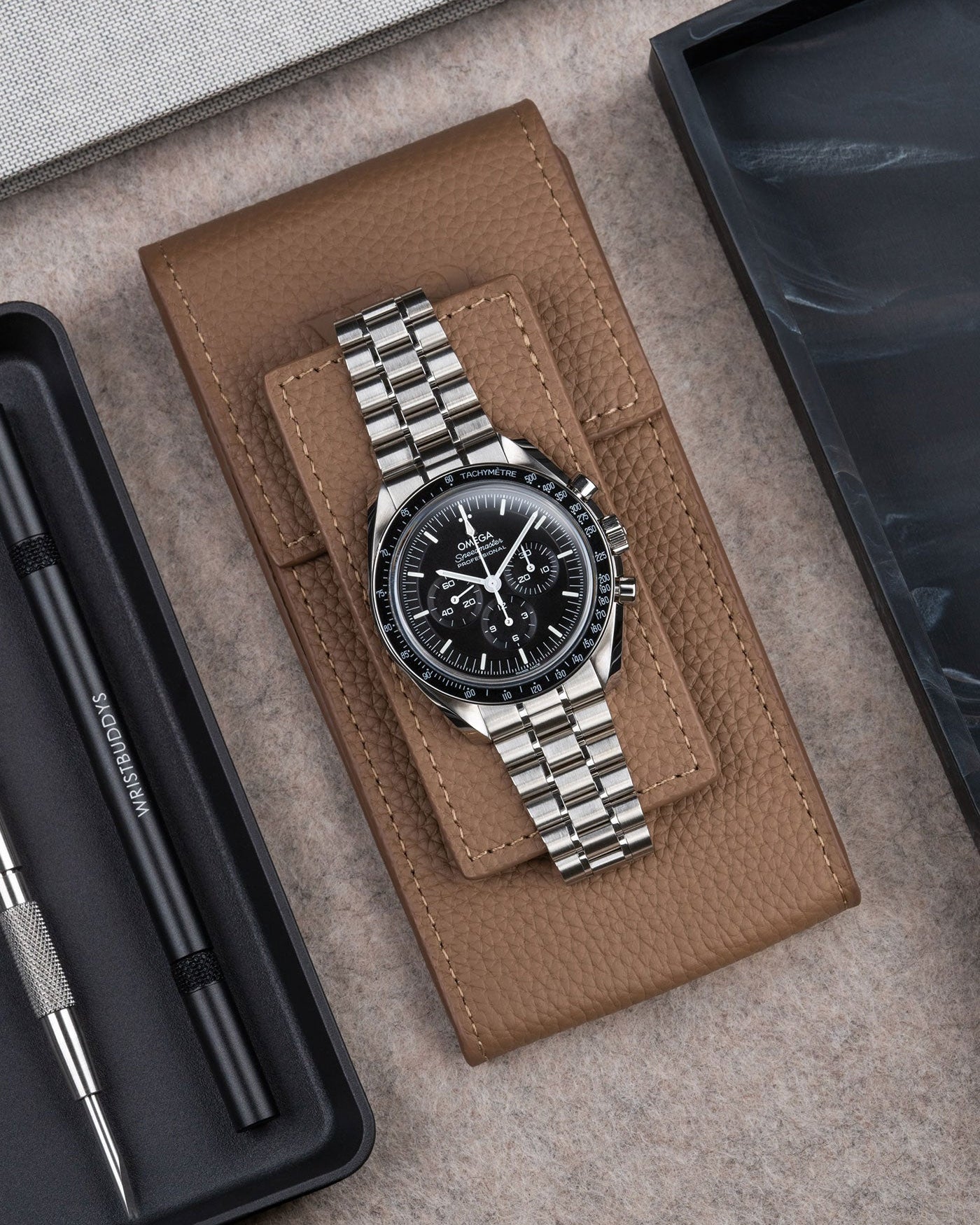 Omega Speedmaster displayed on Brown leather watch pouch by Wristbuddys – elegant flat lay product photo of luxury watch case