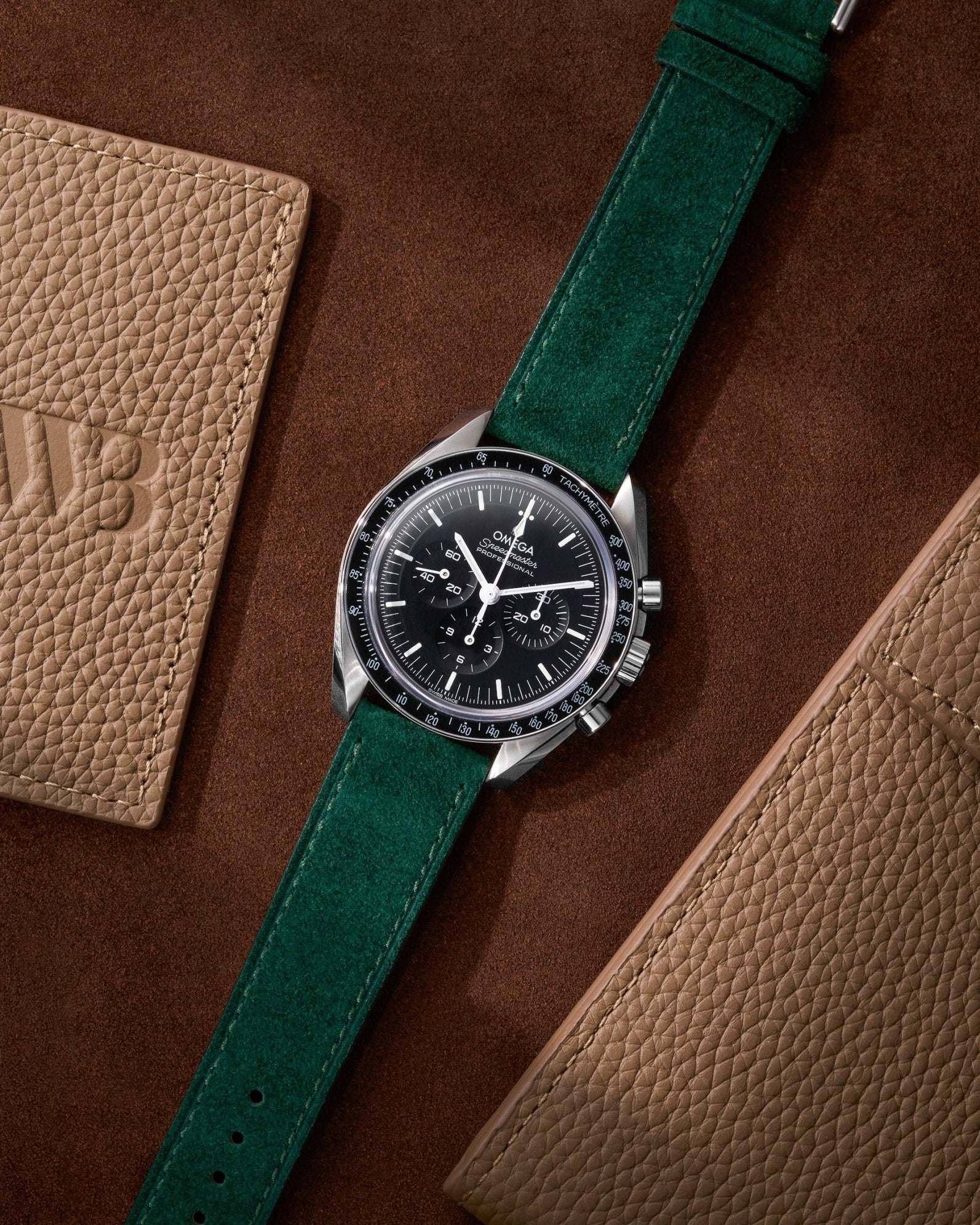 Dark Green Suede Leather Strap 17mm - 21mm on Speedmaster flat lay on brown background