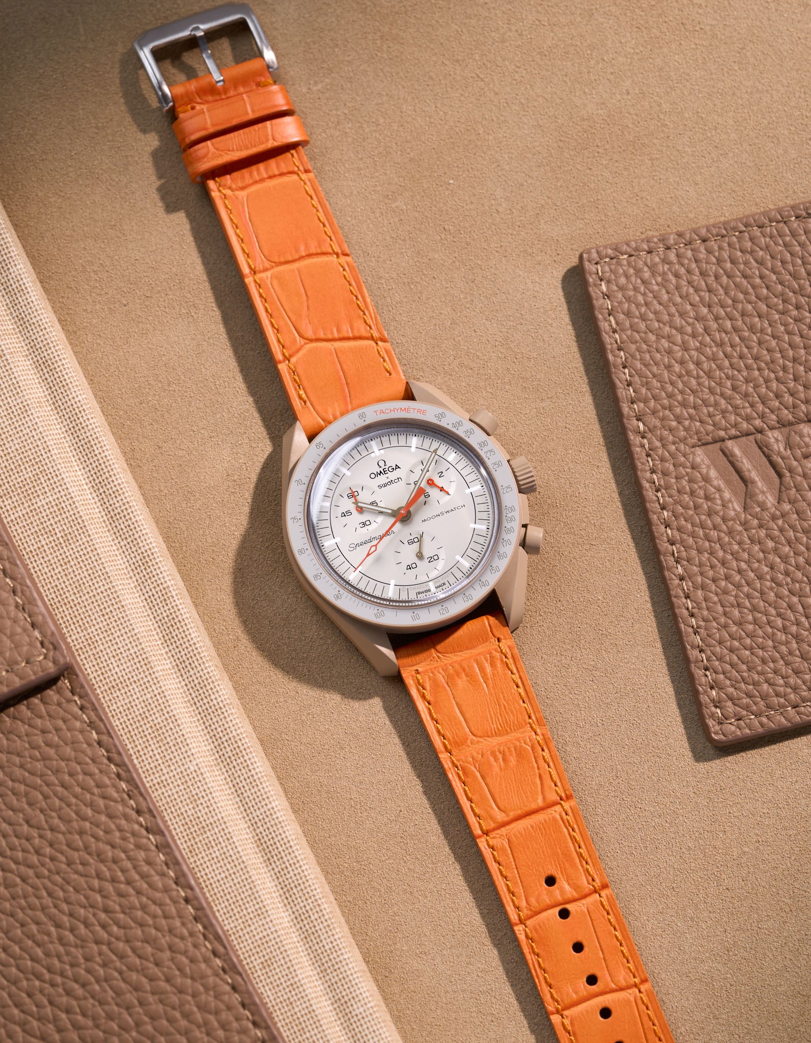 Flat lay of Omega X Swatch MoonSwatch Jupiter with orange embossed alligator leather strap