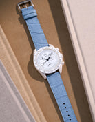 Flat lay of Omega X Swatch MoonSwatch Mission to the Moonphase Full Moon with sky blue embossed alligator leather strap