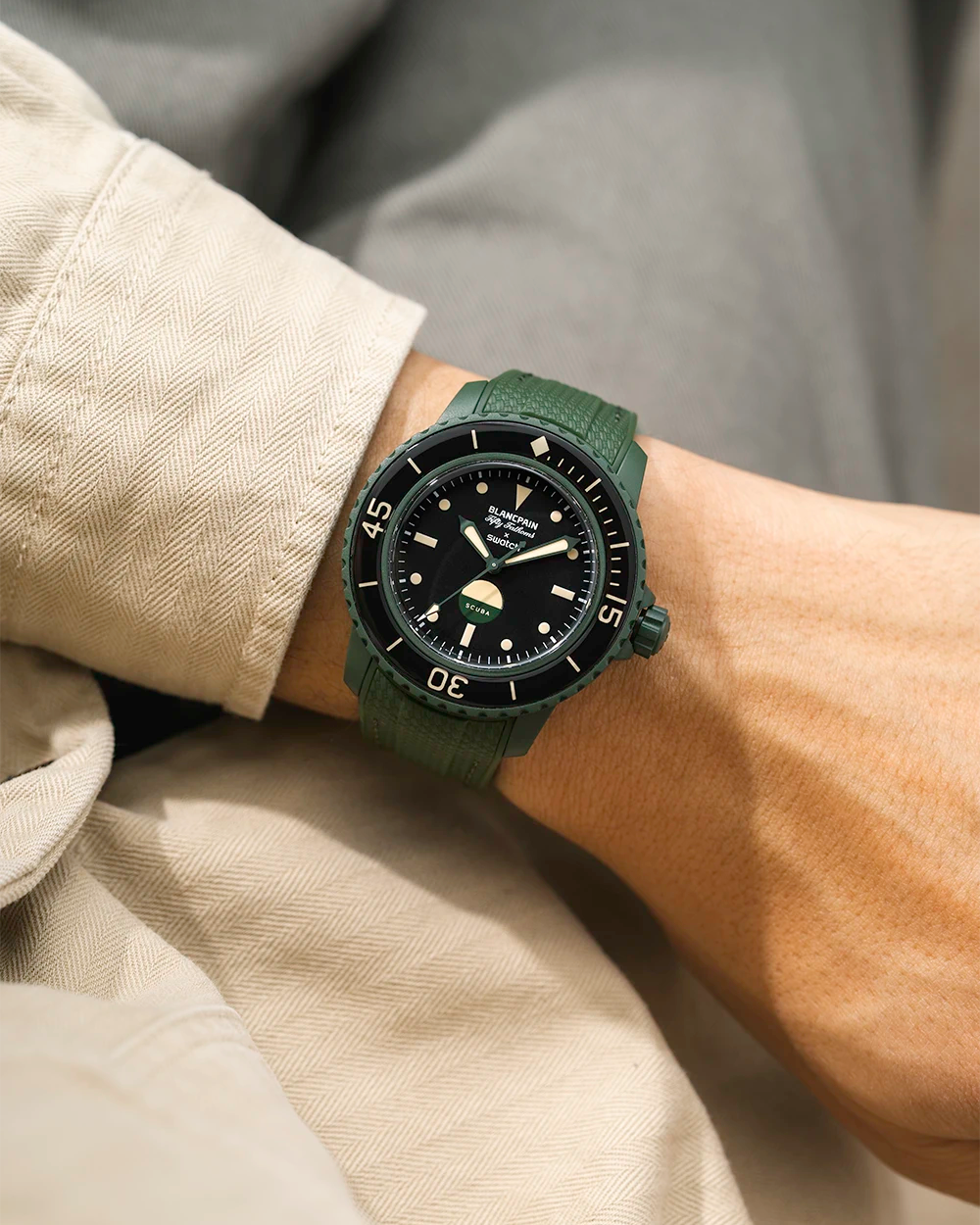 Green Vertech Rubber Watch Strap on a wrist with the Blancpain X Swatch Green Abyss Watch with beige jacket and grey background.