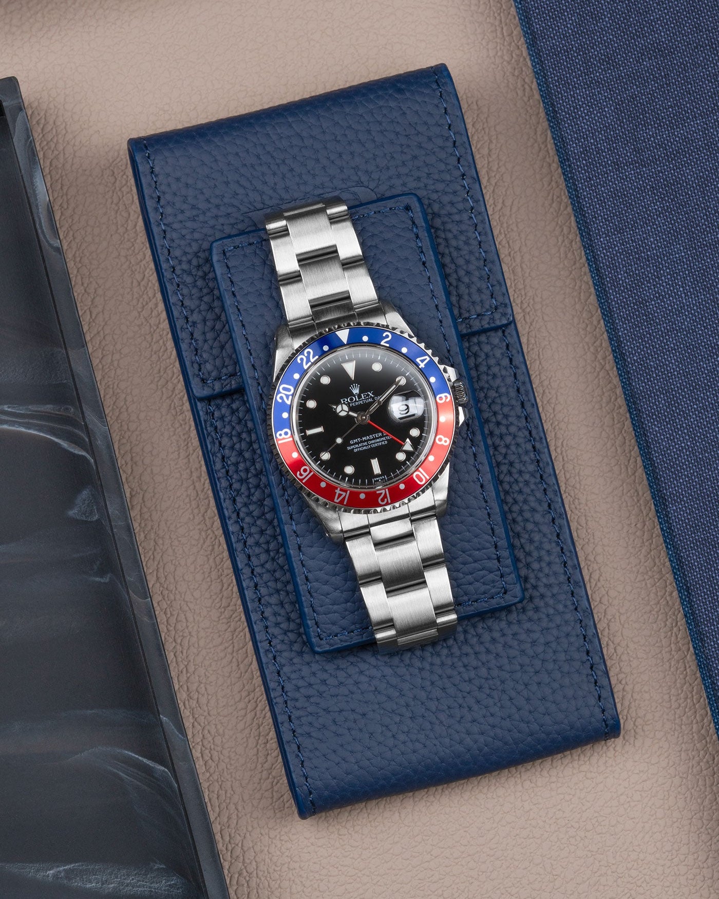 Navy blue leather watch pouch by Wristbuddys with Rolex GMT-Master Pepsi displayed on top – luxury watch storage accessory
