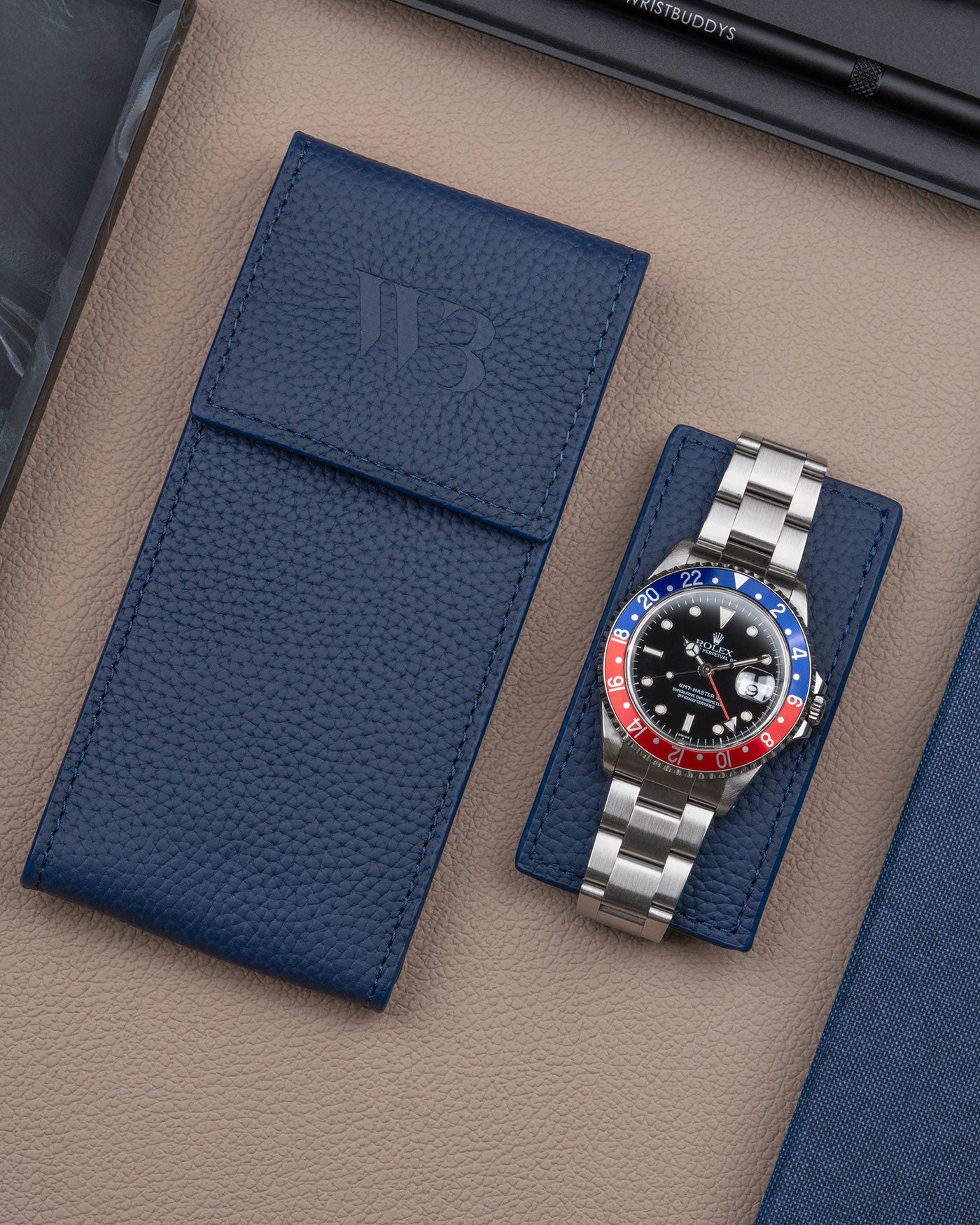 Navy blue leather watch pouch by Wristbuddys with Rolex GMT-Master Pepsi resting on pouch lid – luxury travel case for watches
