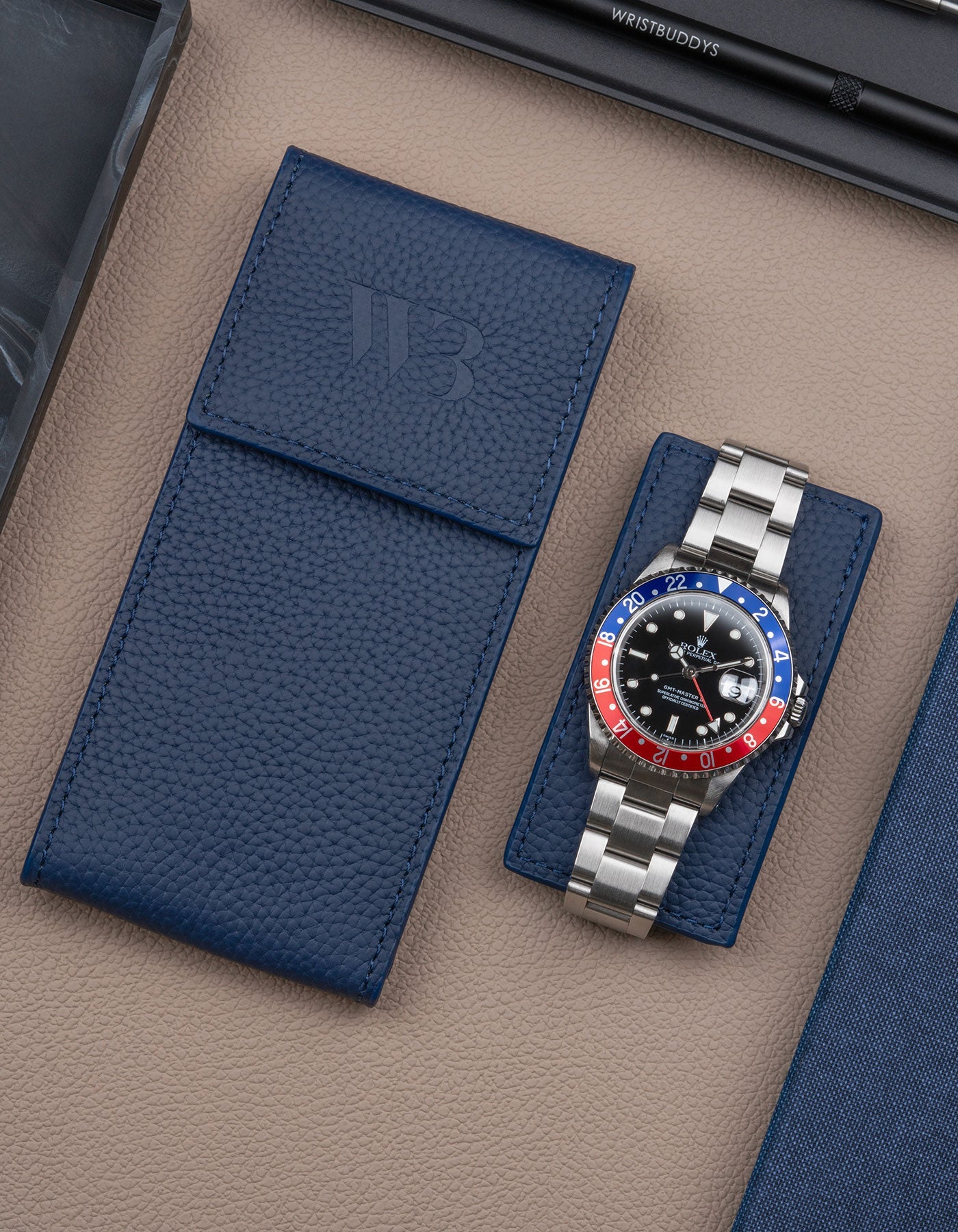 Navy blue leather watch pouch by Wristbuddys with Rolex GMT-Master Pepsi resting on pouch lid – luxury travel case for watches