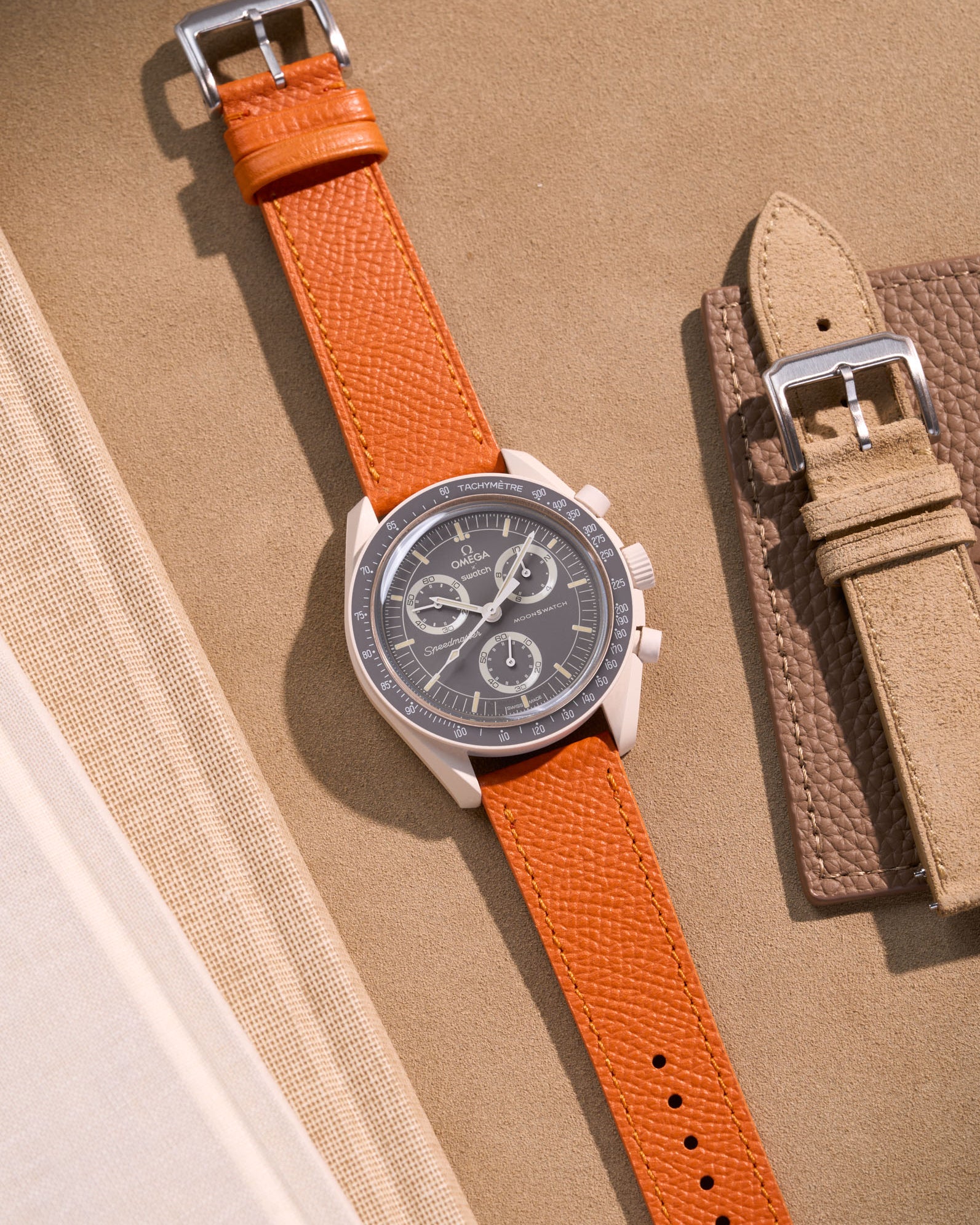 Flat lay of Omega X Swatch Mission on Earth – Desert with Orange Epsom leather strap