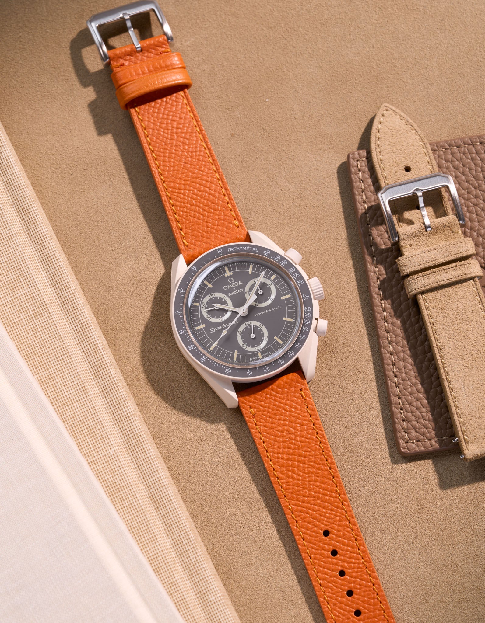 Flat lay of Omega X Swatch Mission on Earth – Desert with Orange Epsom leather strap