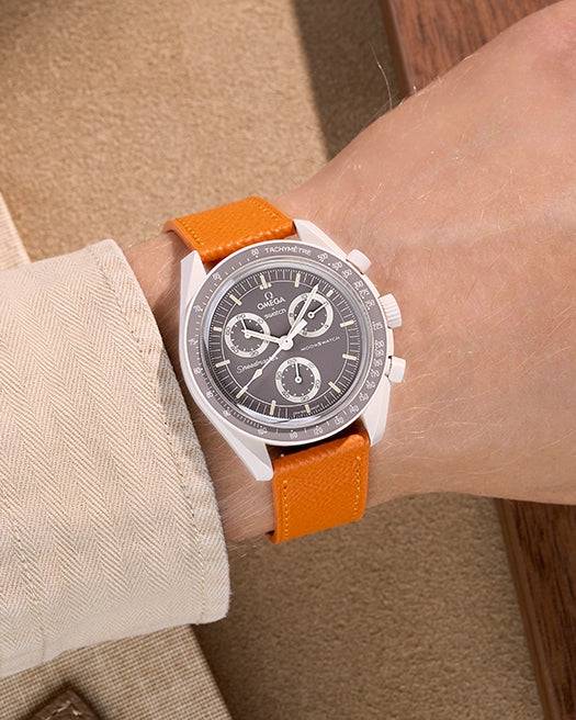 Omega X Swatch Mission on Earth – Desert with Orange Epsom leather strap worn on wrist – styled shot in warm natural tones