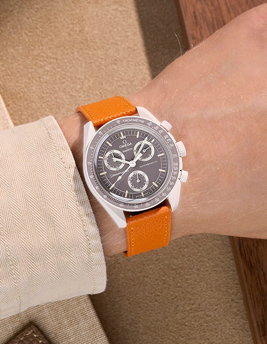 Omega X Swatch Mission on Earth – Desert with Orange Epsom leather strap worn on wrist – styled shot in warm natural tones