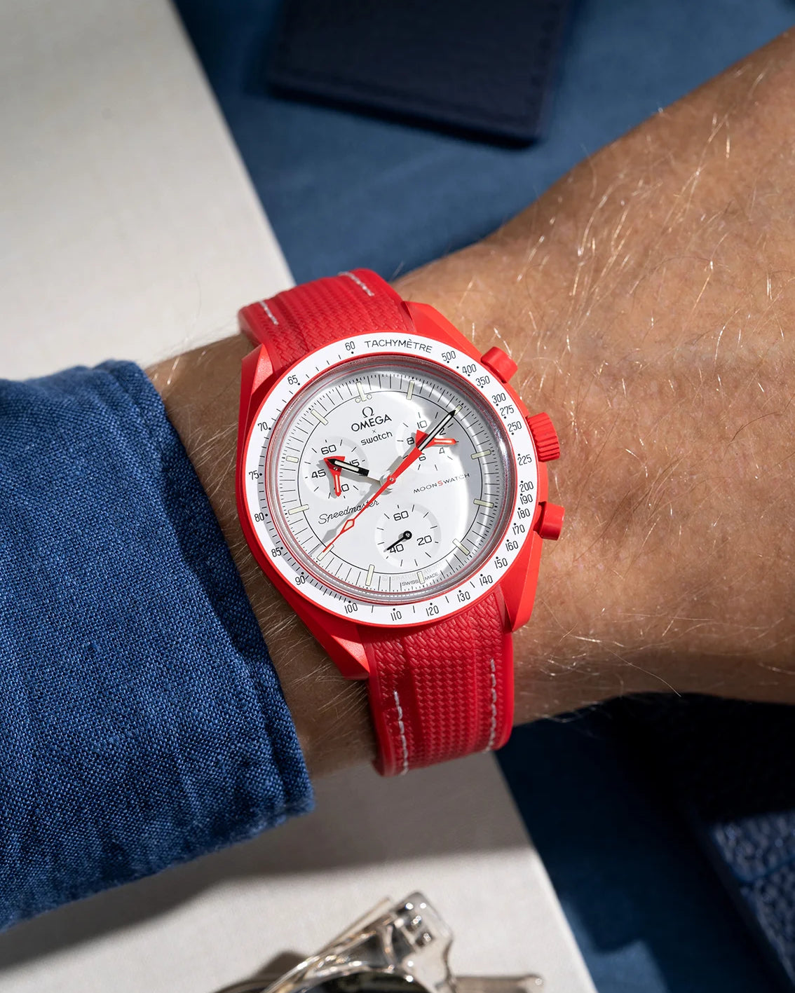 Red curved vertech rubber strap with white stitches photographed on a MoonSwatch Mission to Mars wrist shot