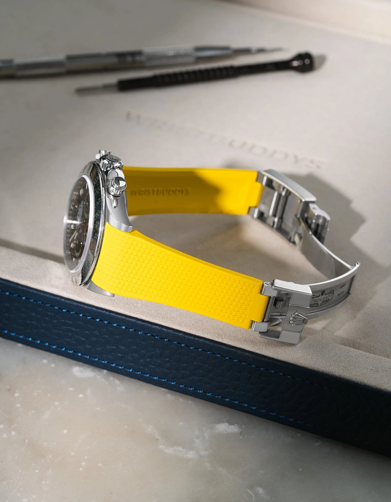 Yellow textured FKM rubber strap for Rolex Daytona 116520, integrated case fit for original clasp, resting on a blue leather valet tray.