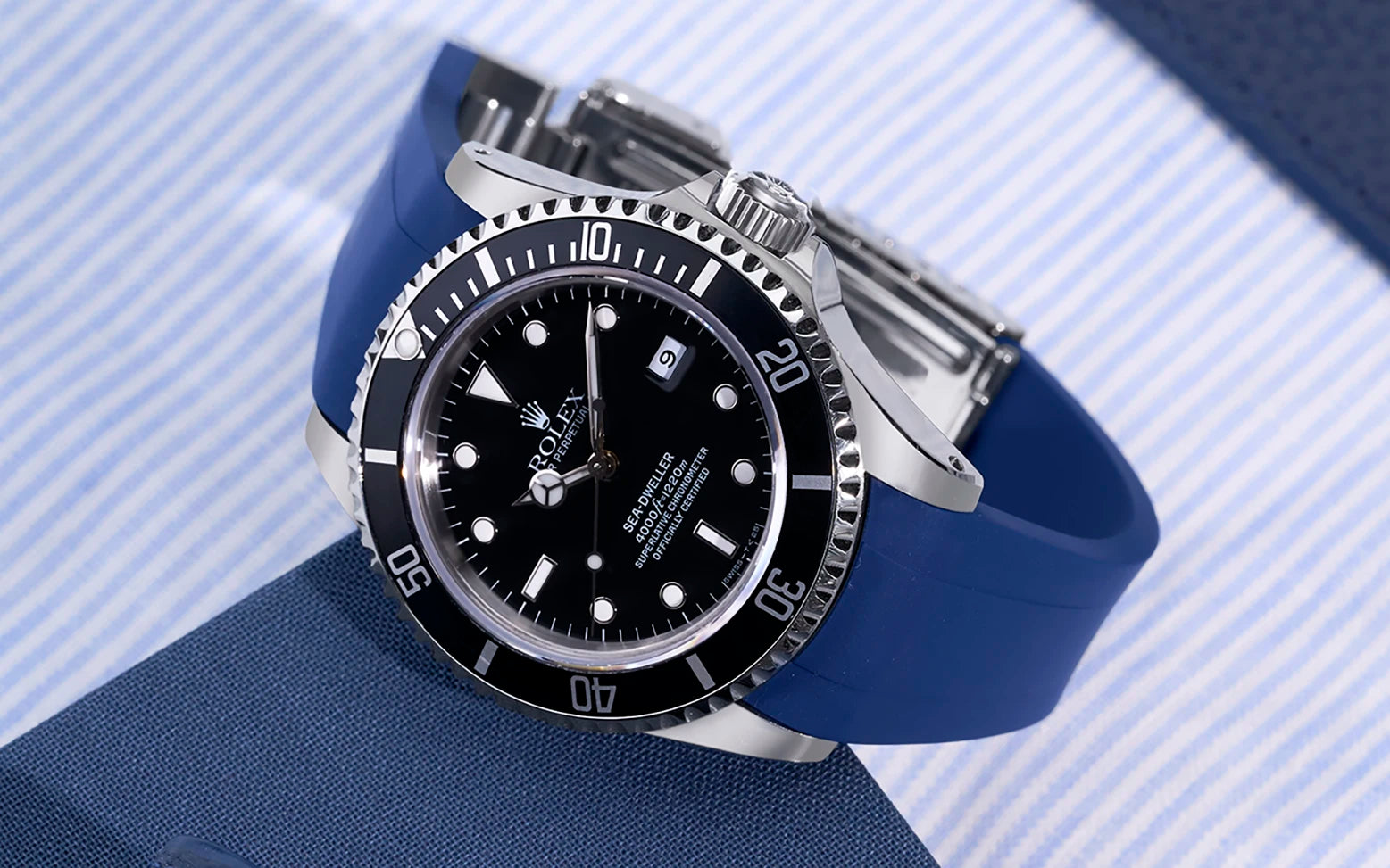 Rolex Sea-Dweller 16600 with curved blue FKM rubber strap from Wristbuddys on wrist with shirt and leather surface