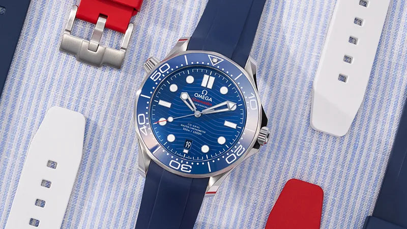 Omega Seamaster 300 Diver with blue FKM rubber strap placed on striped shirt alongside white and red strap variants