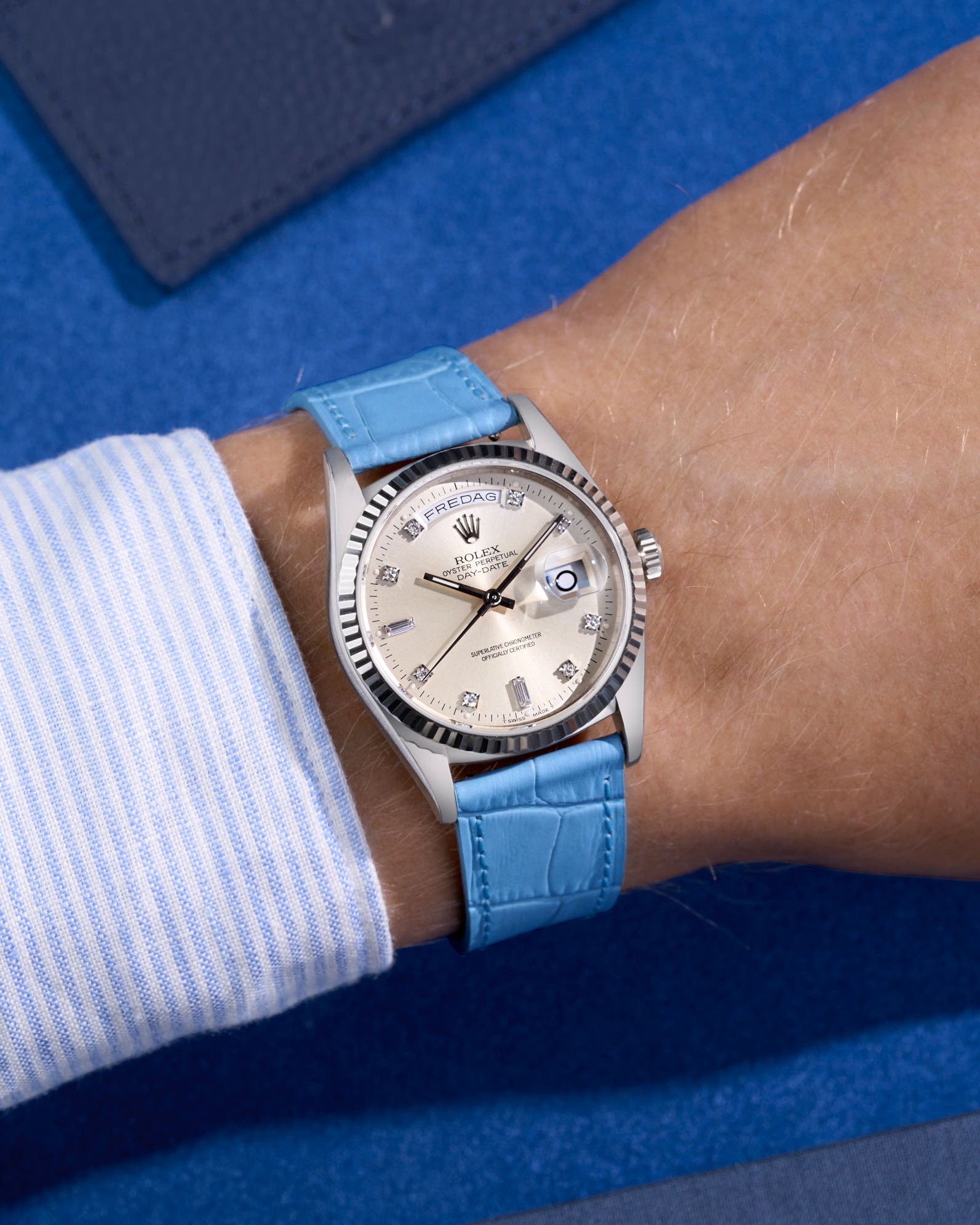 Rolex Daydate with diamond indexes watch with a sky blue alligator leather watch strap on a blue background
