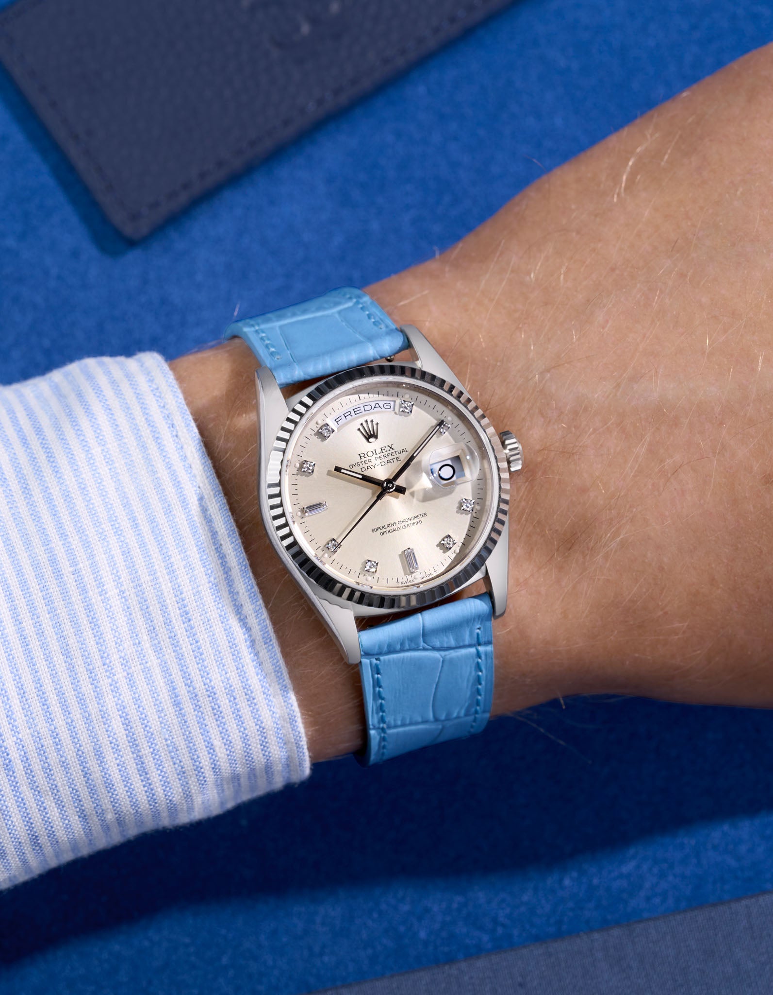 Rolex Daydate with diamond indexes watch with a sky blue alligator leather watch strap on a blue background