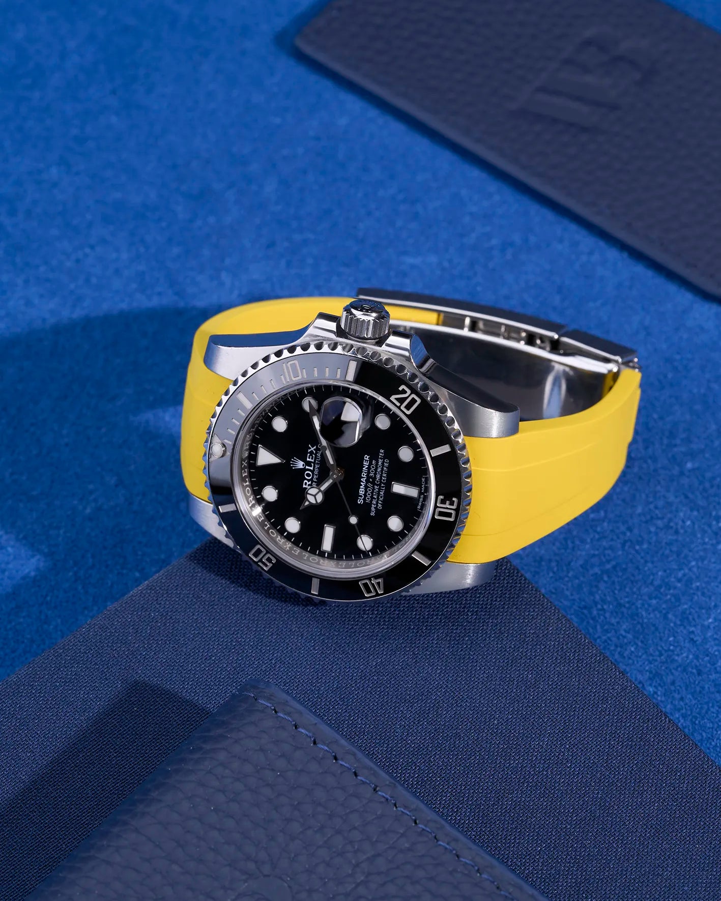Rolex Submariner with integrated yellow rubber strap and original clasp, flat lay view on blue textile background – fits 116610LN and 114060LN