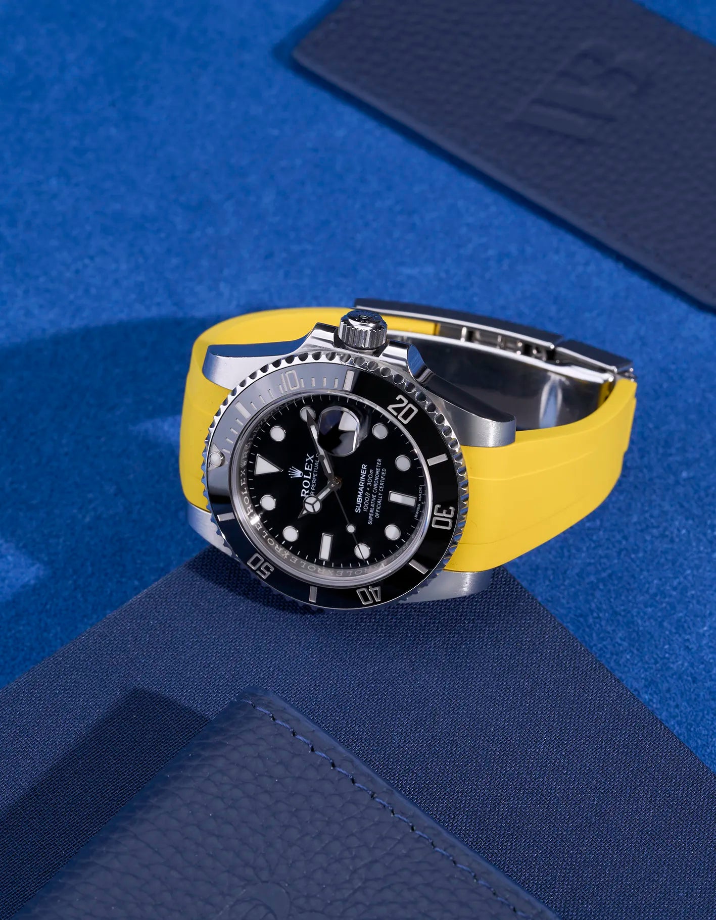 Rolex Submariner with integrated yellow rubber strap and original clasp, flat lay view on blue textile background – fits 116610LN and 114060LN
