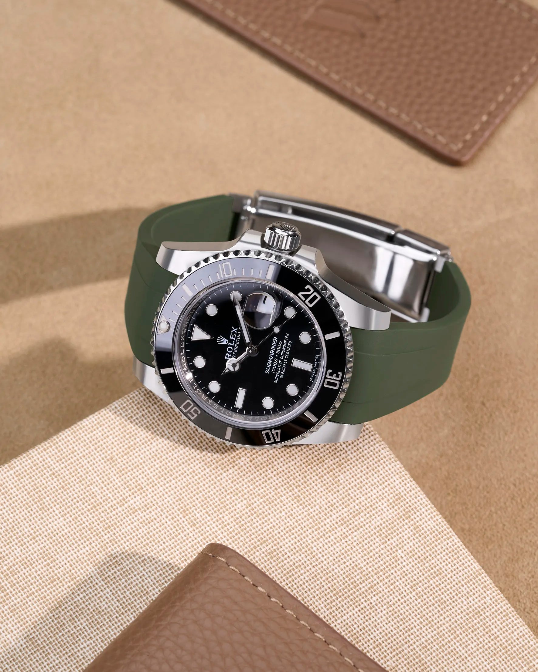 Rolex Submariner 116610LN with green FKM rubber strap on beige leather background