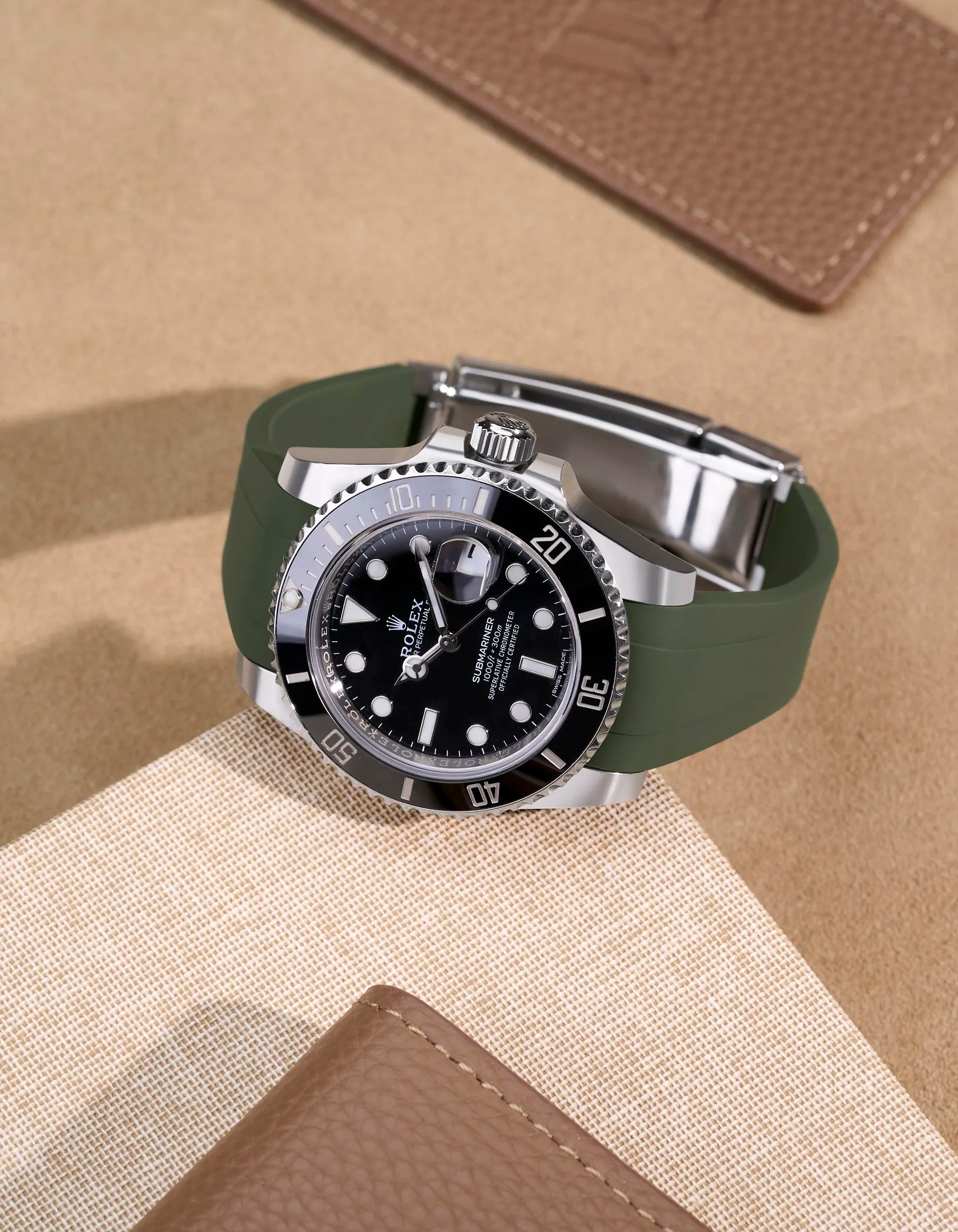 Rolex Submariner 116610LN with green FKM rubber strap on beige leather background